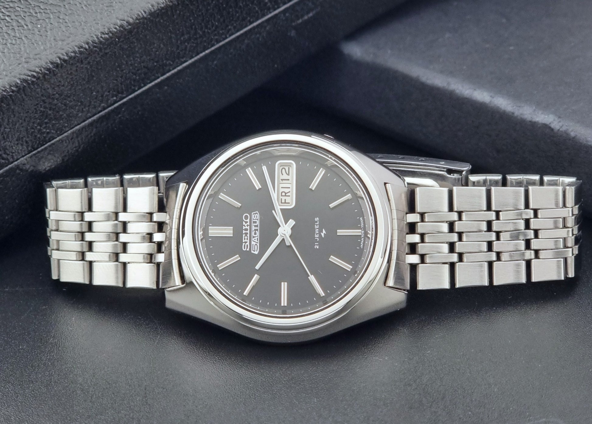 Vintage Seiko 5 Actus Wristwatch 7019-7060 with a stainless steel bracelet on a dark surface front view
