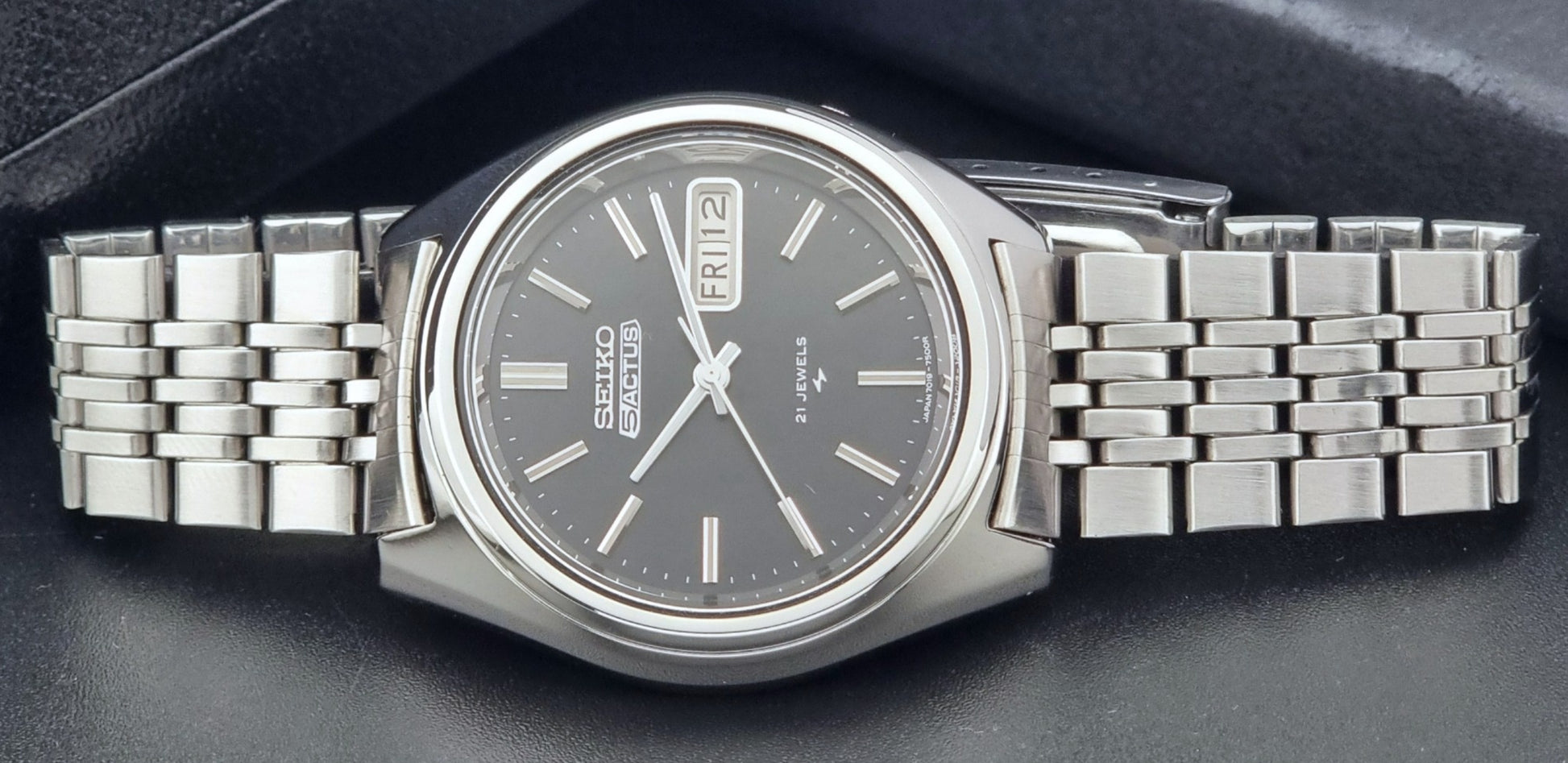 Vintage Seiko 5 Actus Wristwatch 7019-7060 with a stainless steel bracelet on a dark surface close up dial view