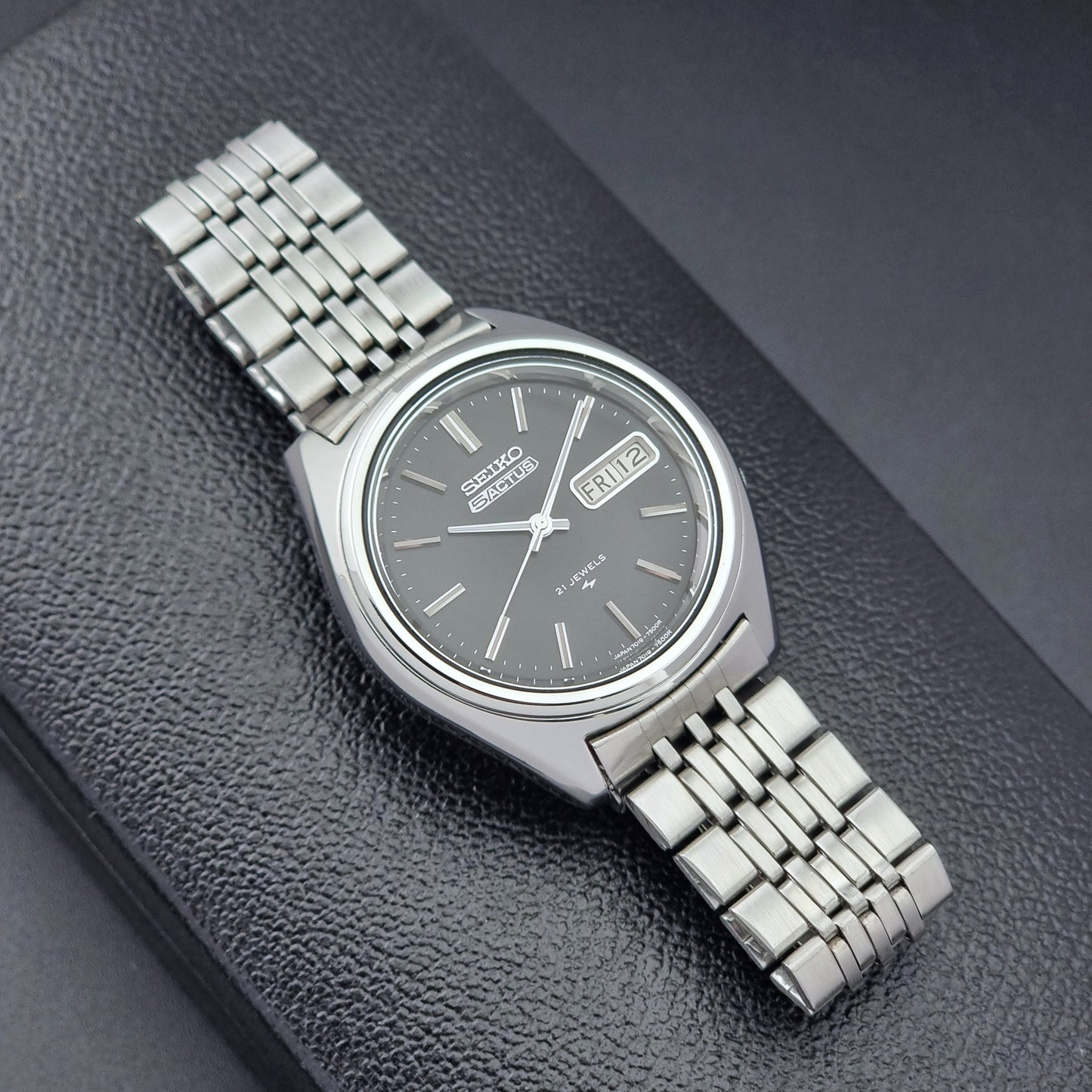 Vintage Seiko 5 Actus Wristwatch 7019-7060 with a stainless steel bracelet on a dark surface front