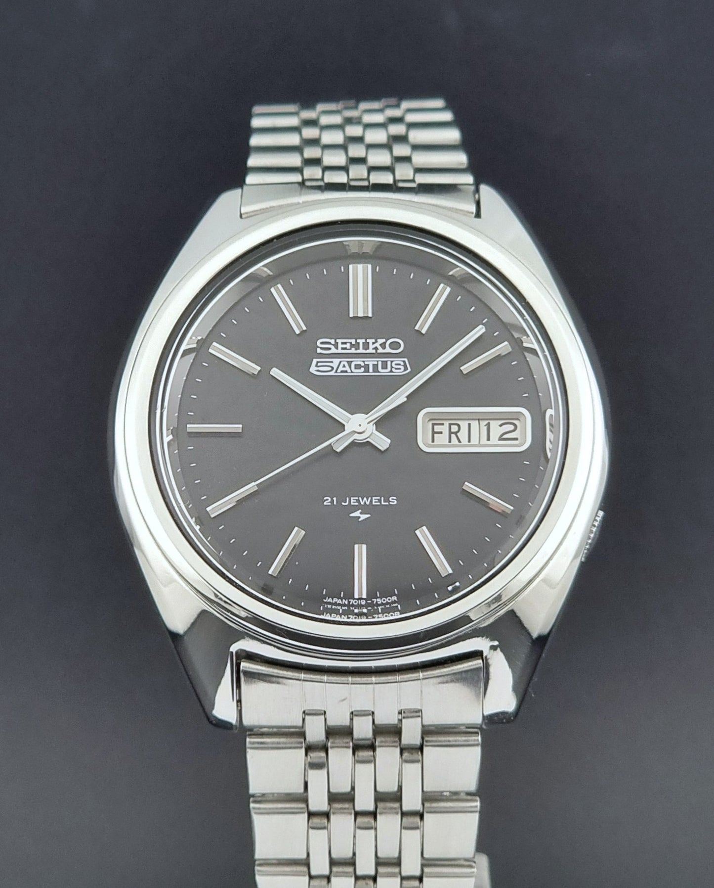Vintage Seiko 5 Actus Wristwatch 7019-7060 with a stainless steel bracelet on a dark surface dial view