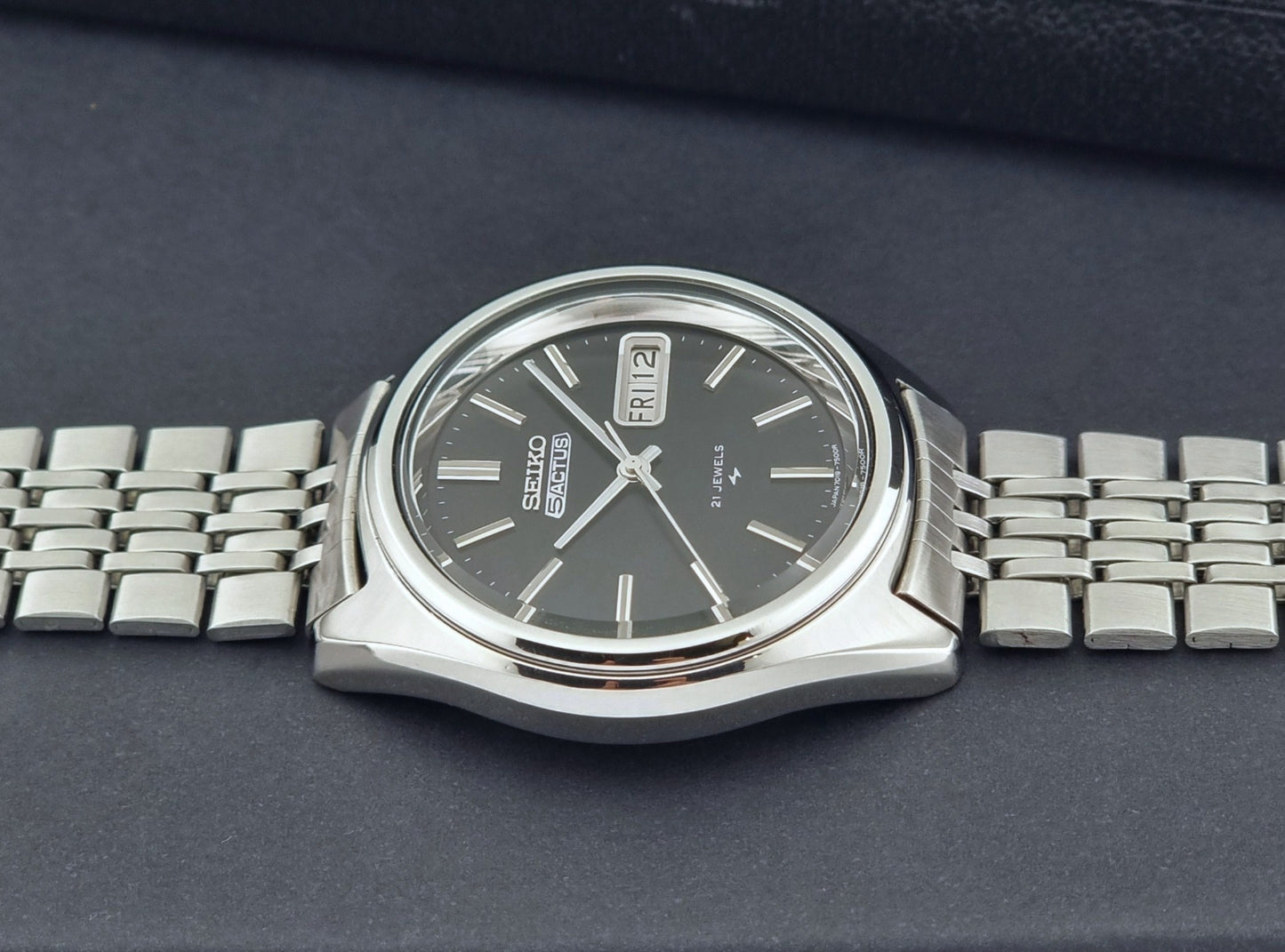 Vintage Seiko 5 Actus Wristwatch 7019-7060 with a stainless steel bracelet on a dark surface side profile view