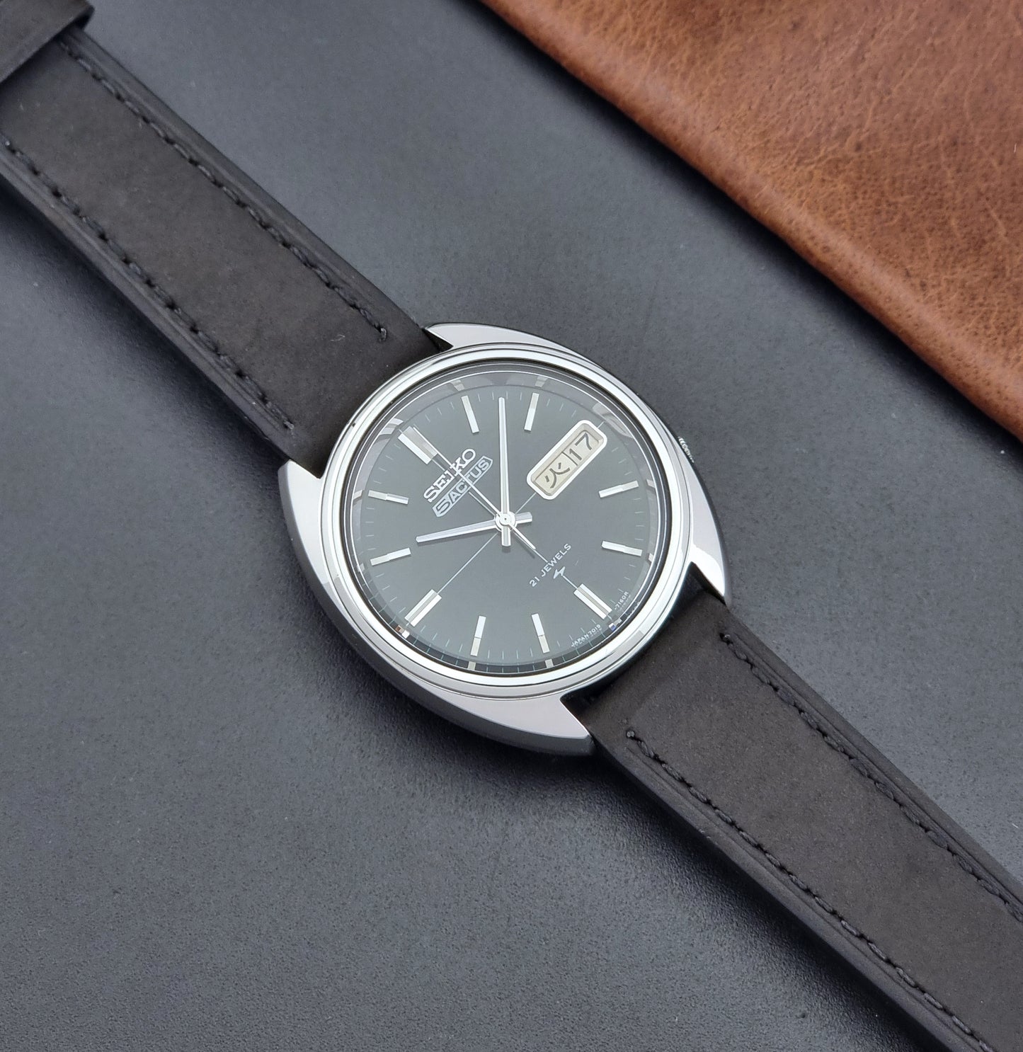 Vintage Seiko 5 Actus Wristwatch 7019-7070 watch with a dark leather strap on a gray surface dial
