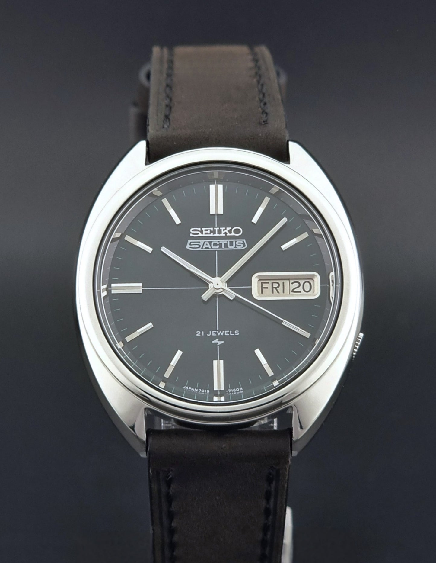 Vintage Seiko 5 Actus Wristwatch 7019-7070 watch with a dark leather strap on a gray surface close dial view