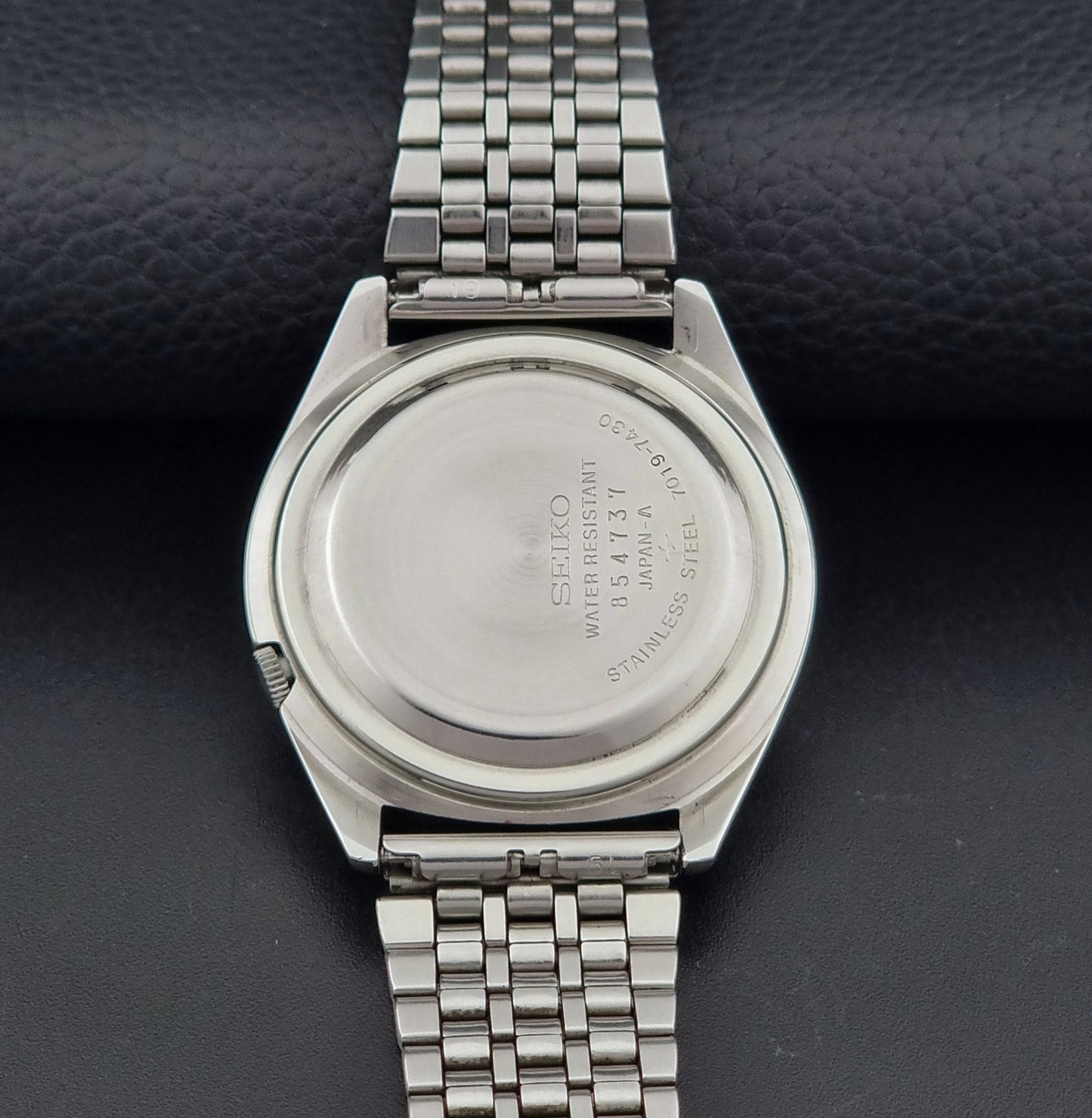 Vintage Seiko Actus Wristwatch 7019-7430 with a blue dial and bracelet on a dark back ground case back view