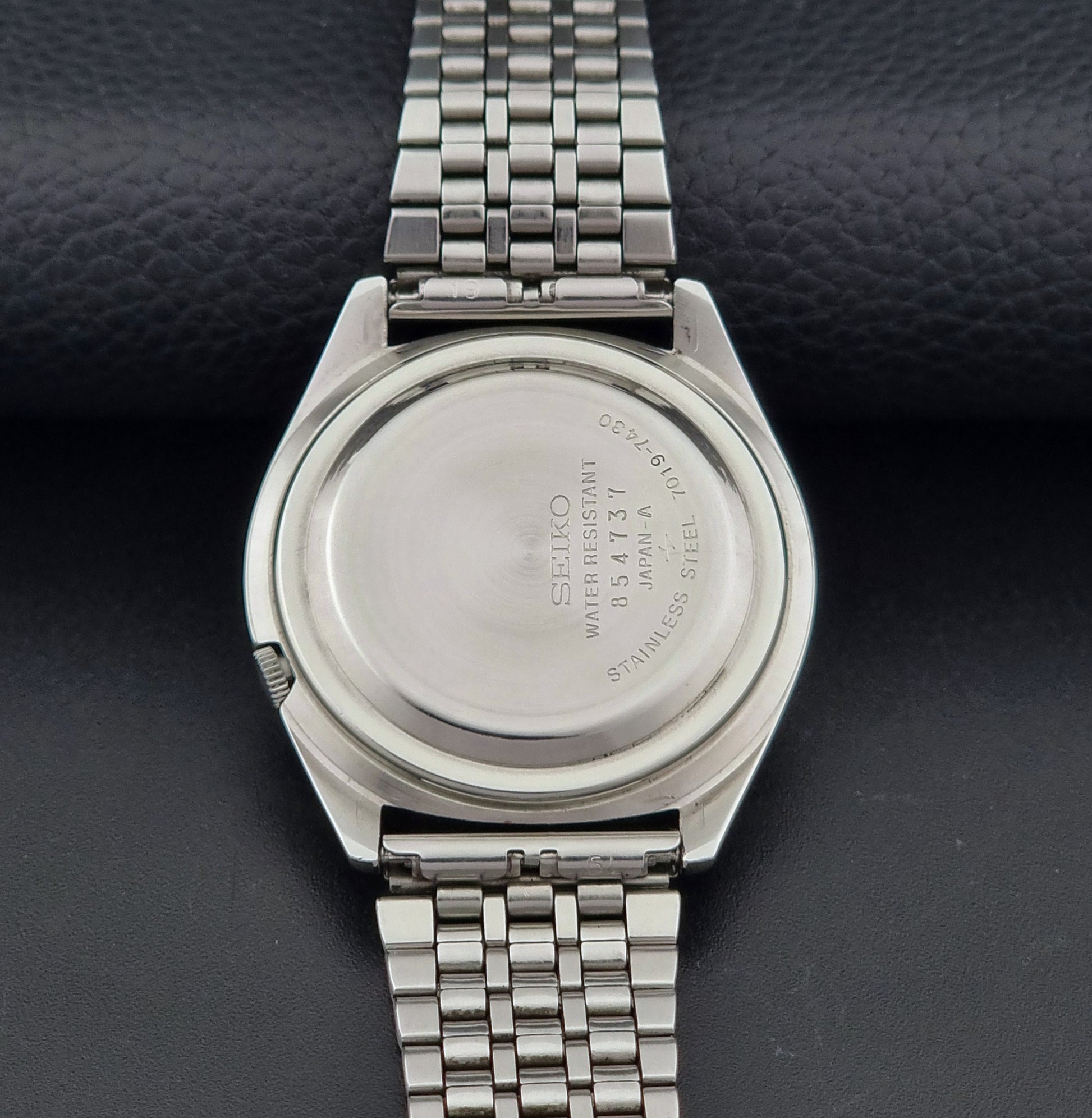 Vintage Seiko Actus Wristwatch 7019-7430 with a blue dial and bracelet on a dark back ground case back view