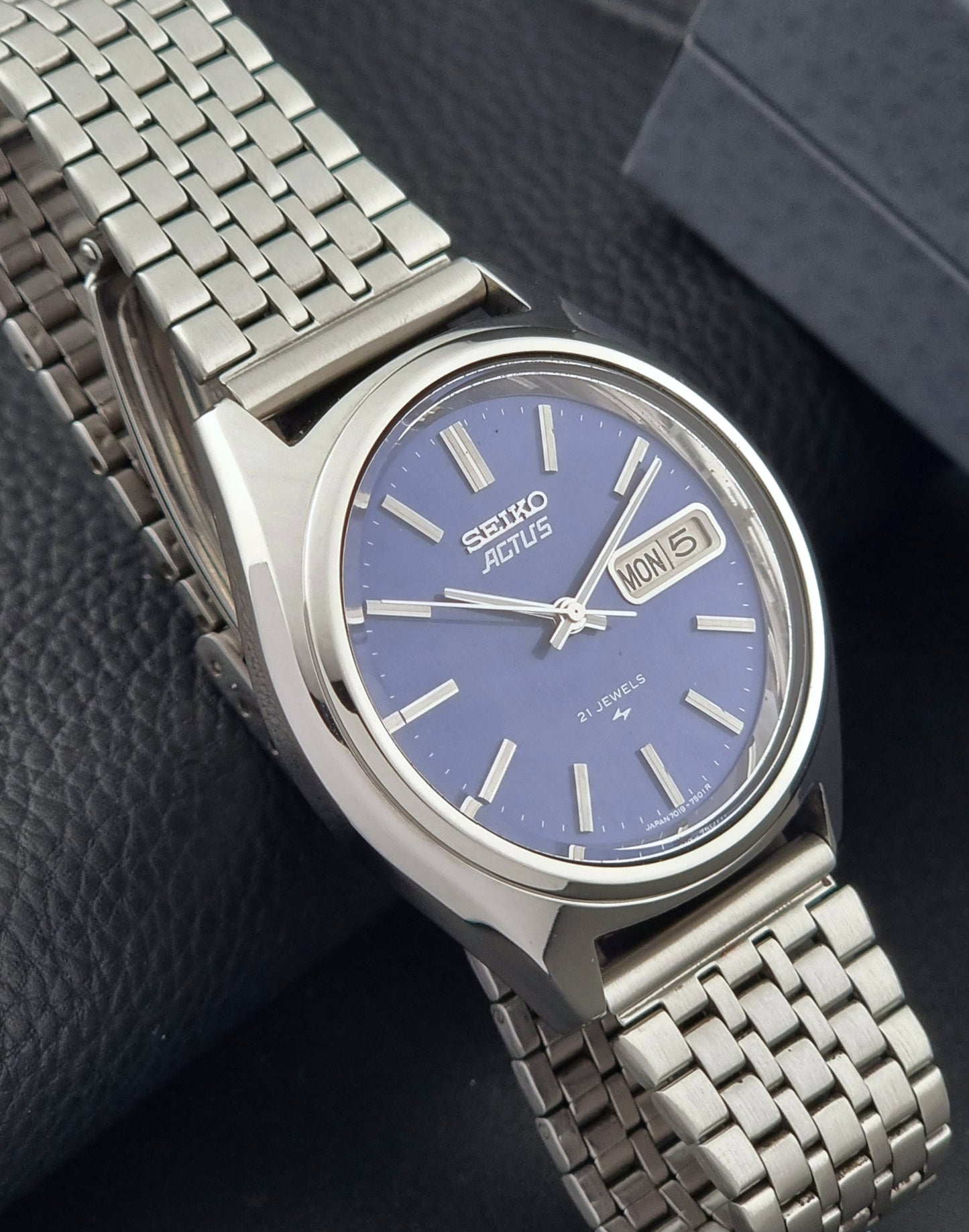 Vintage Seiko Actus Wristwatch 7019-7430 with a blue dial and bracelet on a dark back ground side view