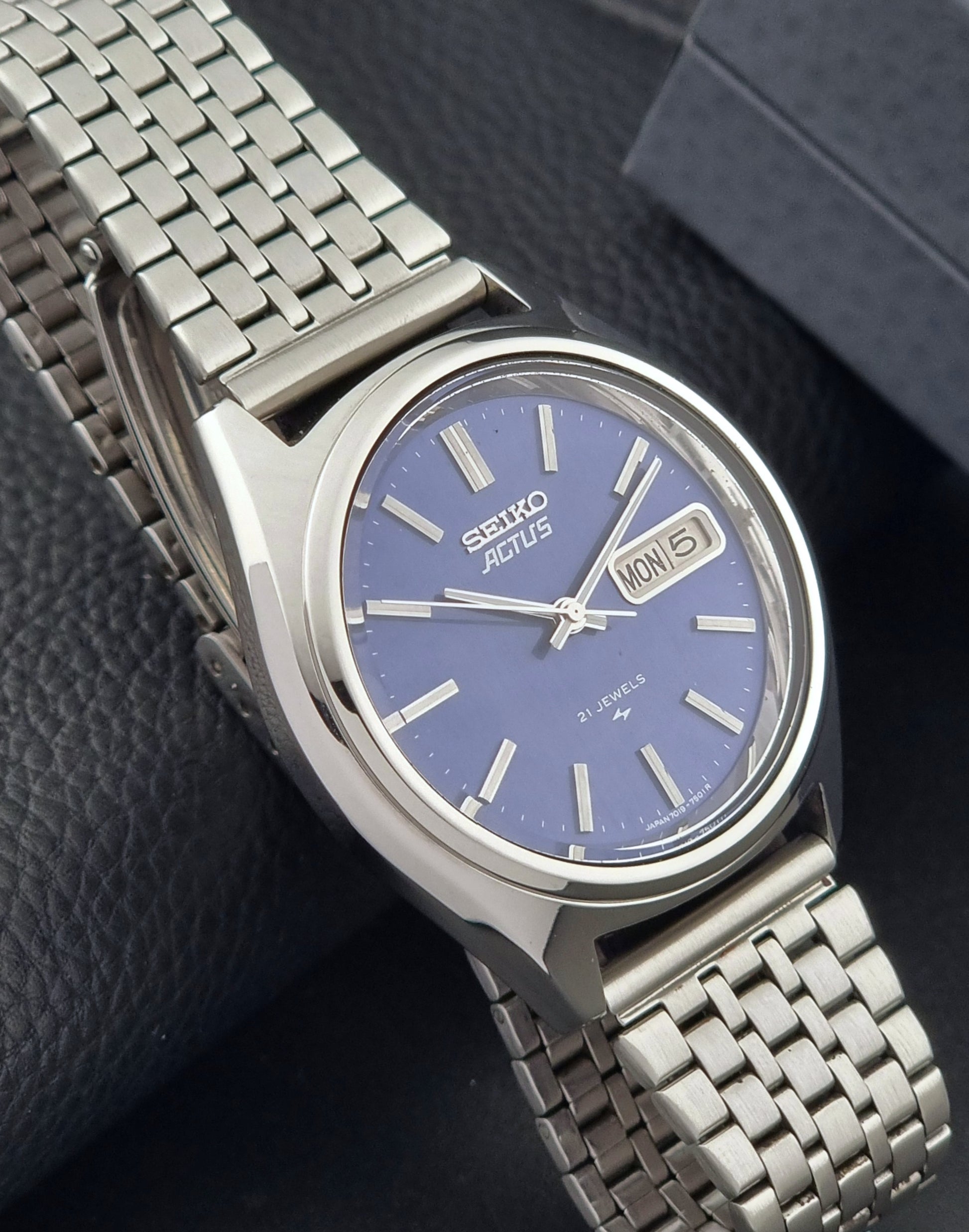 Vintage Seiko Actus Wristwatch 7019-7430 with a blue dial and bracelet on a dark back ground side view