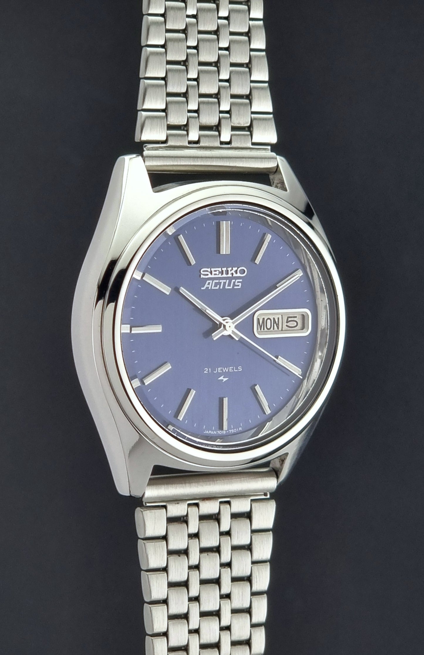 Vintage Seiko Actus Wristwatch 7019-7430 with a blue dial and bracelet on a dark back ground side profile view