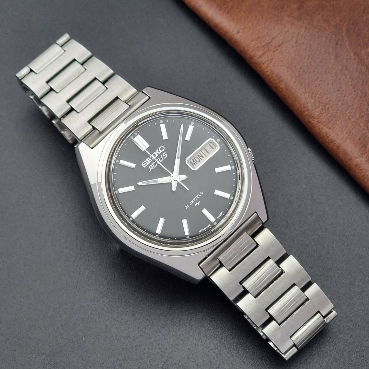 Vintage Seiko Actus Wristwatch 7019-8010 with a Black dial and bracelet on a dark back ground dial