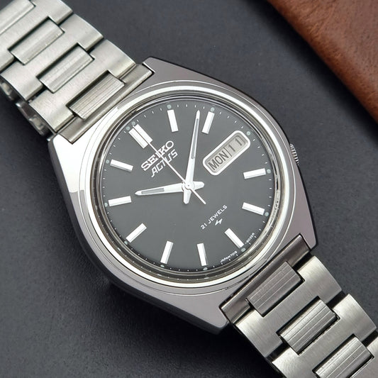Vintage Seiko Actus Wristwatch 7019-8010 with a Black dial and bracelet on a dark back ground close up dial view