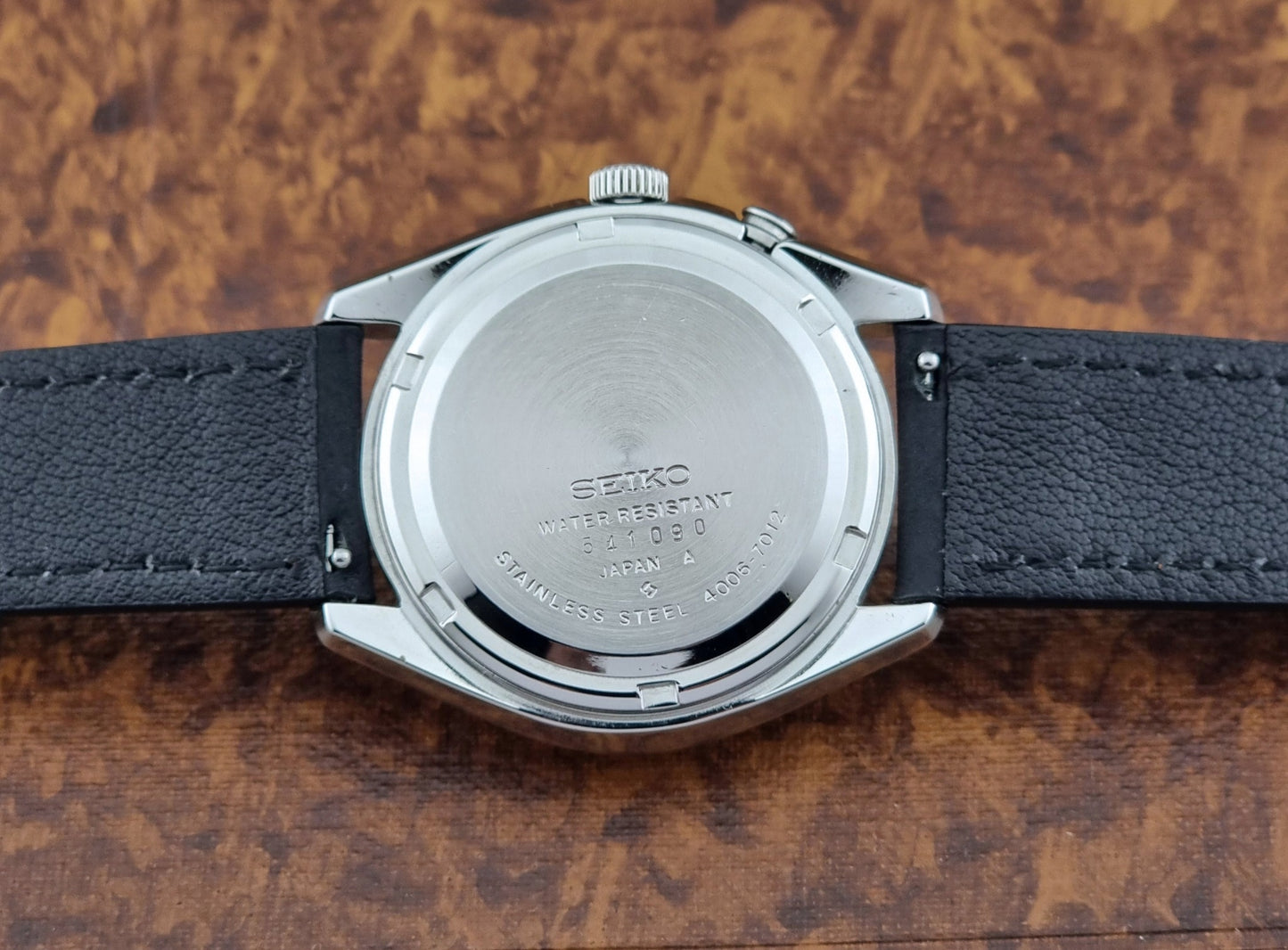 Vintage Seiko Bell-matic Wristwatch with black leather strap on a brown background case back view