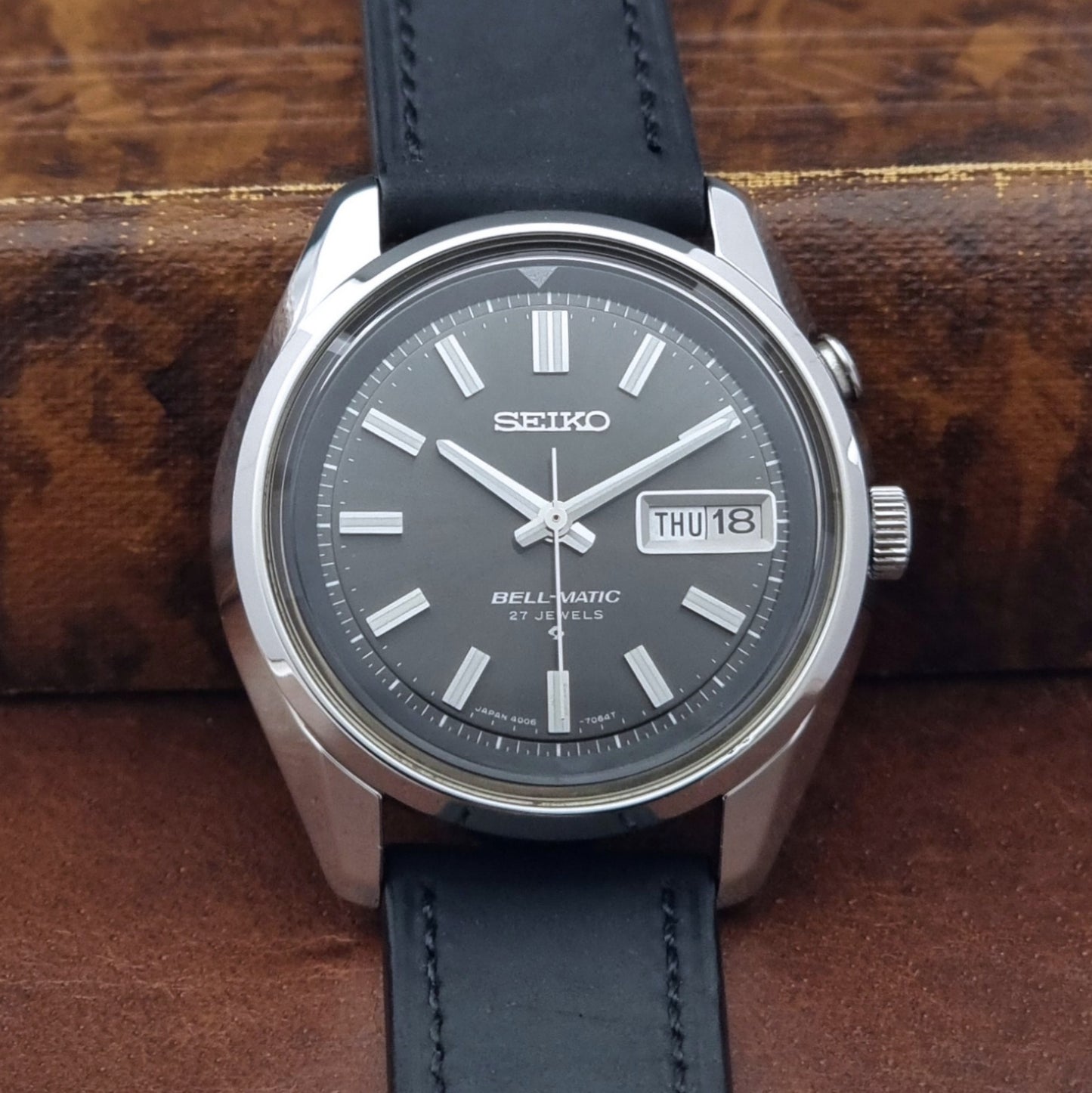 Vintage Seiko Bell-matic Wristwatch with black leather strap on a brown background close up dial view