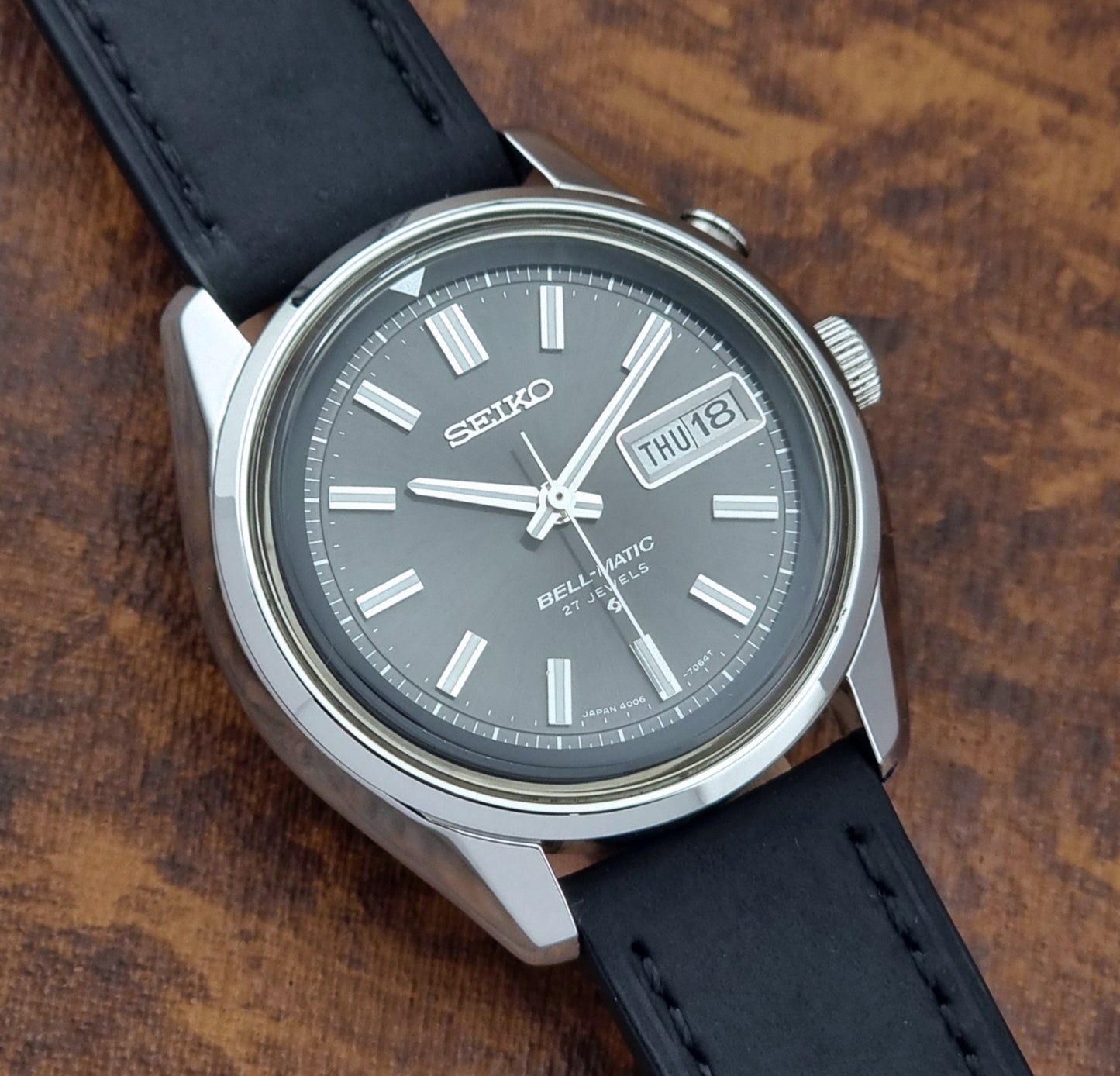 Vintage Seiko Bell-matic Wristwatch with black leather strap on a brown background close dial view