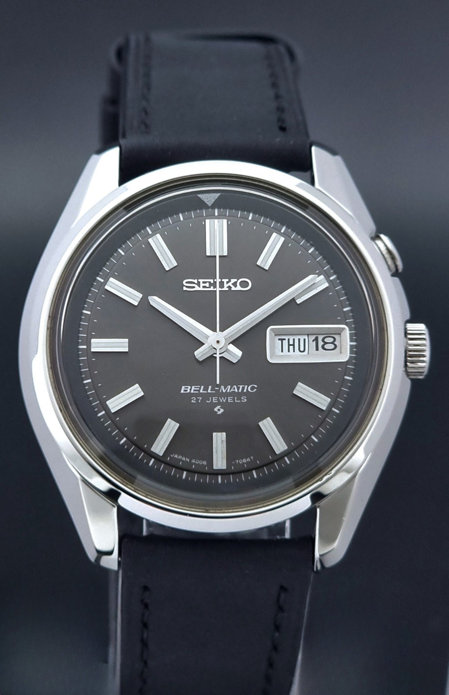 Vintage Seiko Bell-matic Wristwatch with black leather strap on a dark background dial view