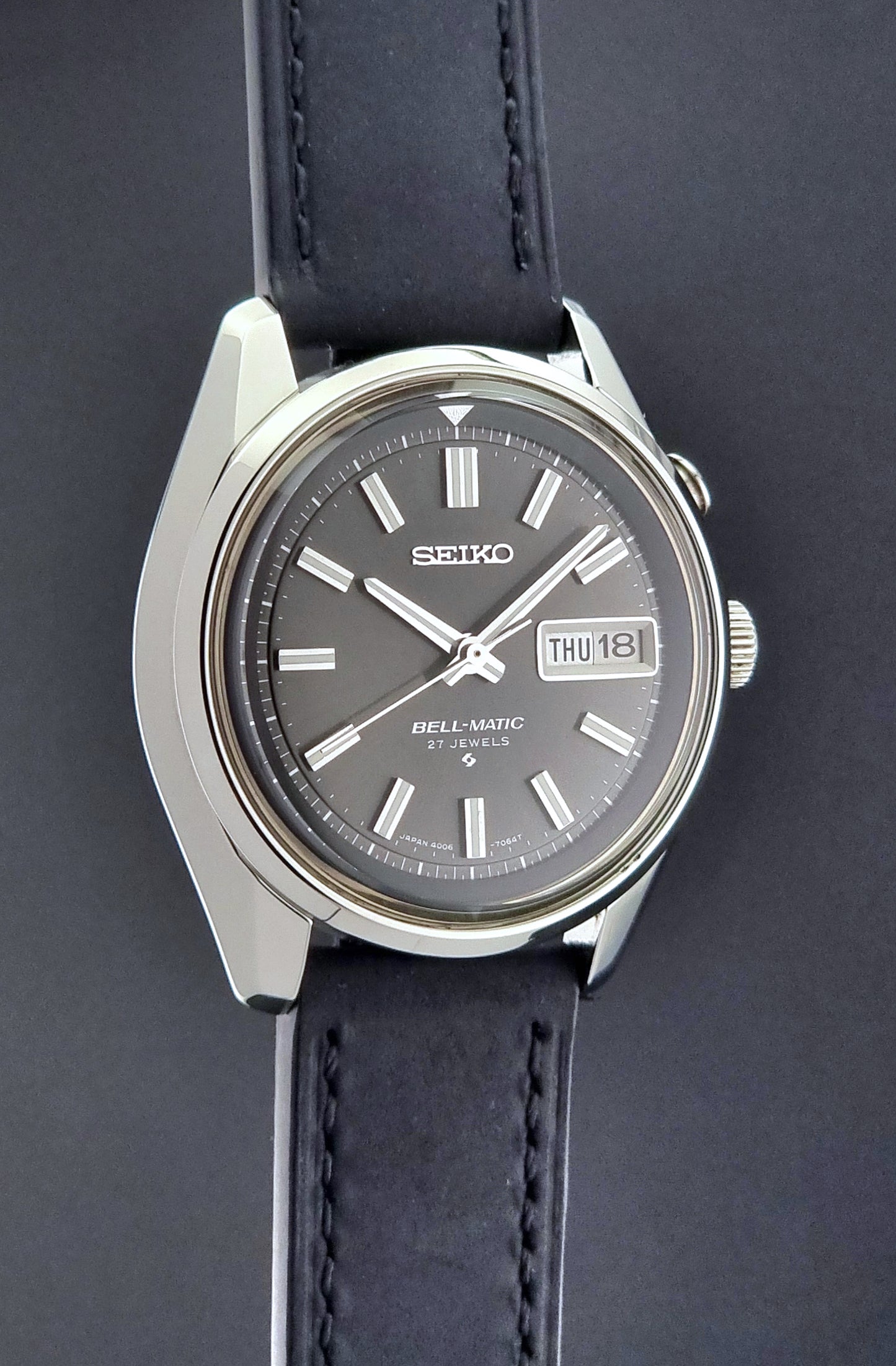 Vintage Seiko Bell-matic Wristwatch with black leather strap on a dark background side profile