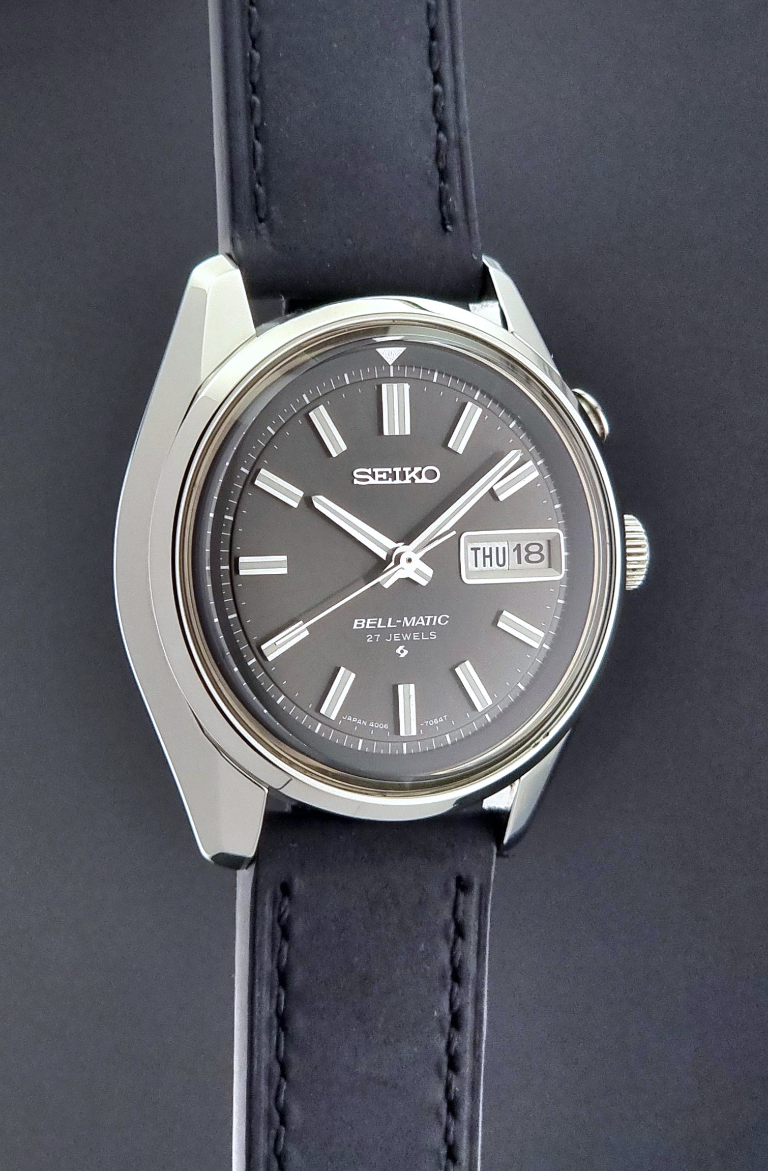 Vintage Seiko Bell-matic Wristwatch with black leather strap on a dark background side profile