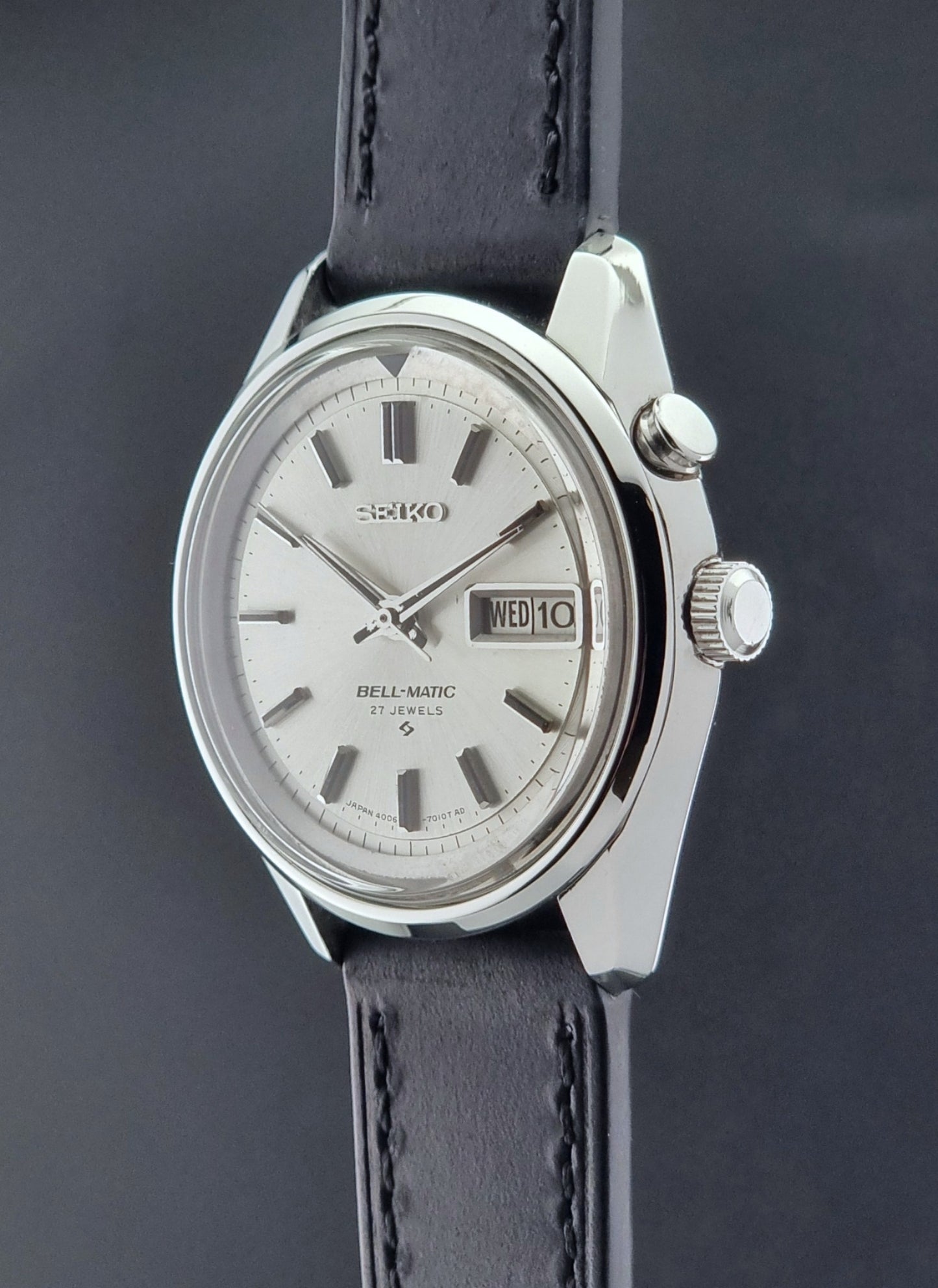 Vintage Seiko Alarm Wristwatch Bell-Matic 4006-7010 with black leather strap on a dark surface crown profile view