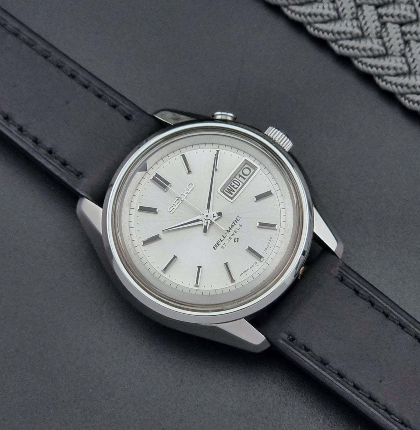 Vintage Seiko Alarm Wristwatch Bell-Matic 4006-7010 with black leather strap on a dark surface close up dial view