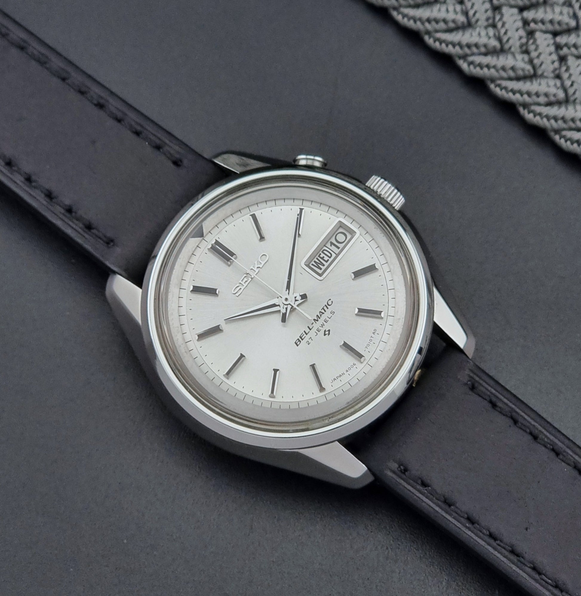Vintage Seiko Alarm Wristwatch Bell-Matic 4006-7010 with black leather strap on a dark surface close up dial view