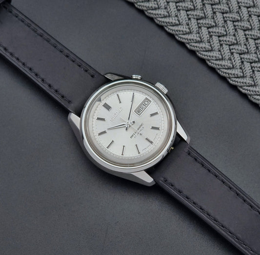 Vintage Seiko Alarm Wristwatch Bell-Matic 4006-7010 with black leather strap on a dark surface dial