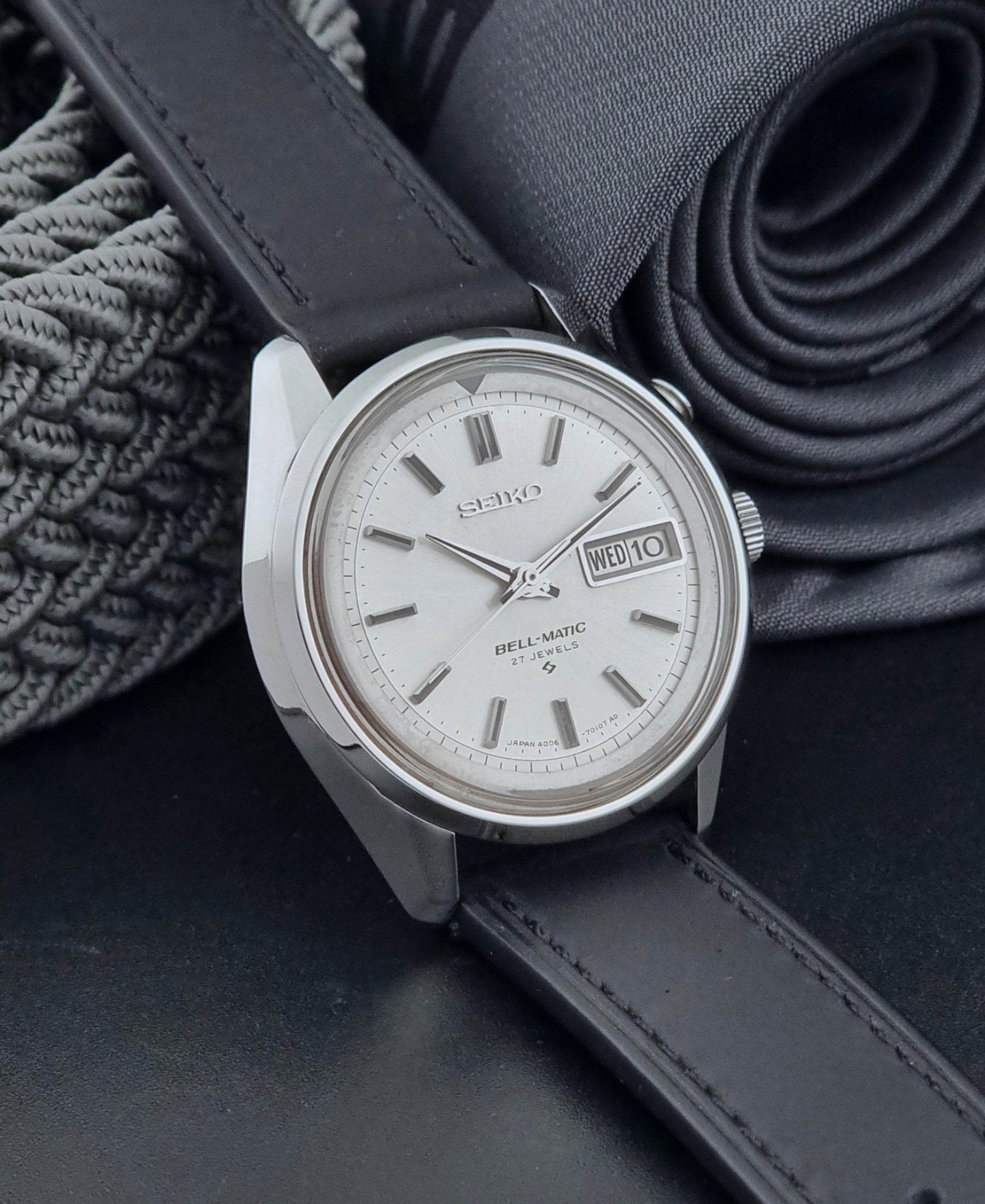Vintage Seiko Alarm Wristwatch Bell-Matic 4006-7010 with black leather strap on a dark surface side view