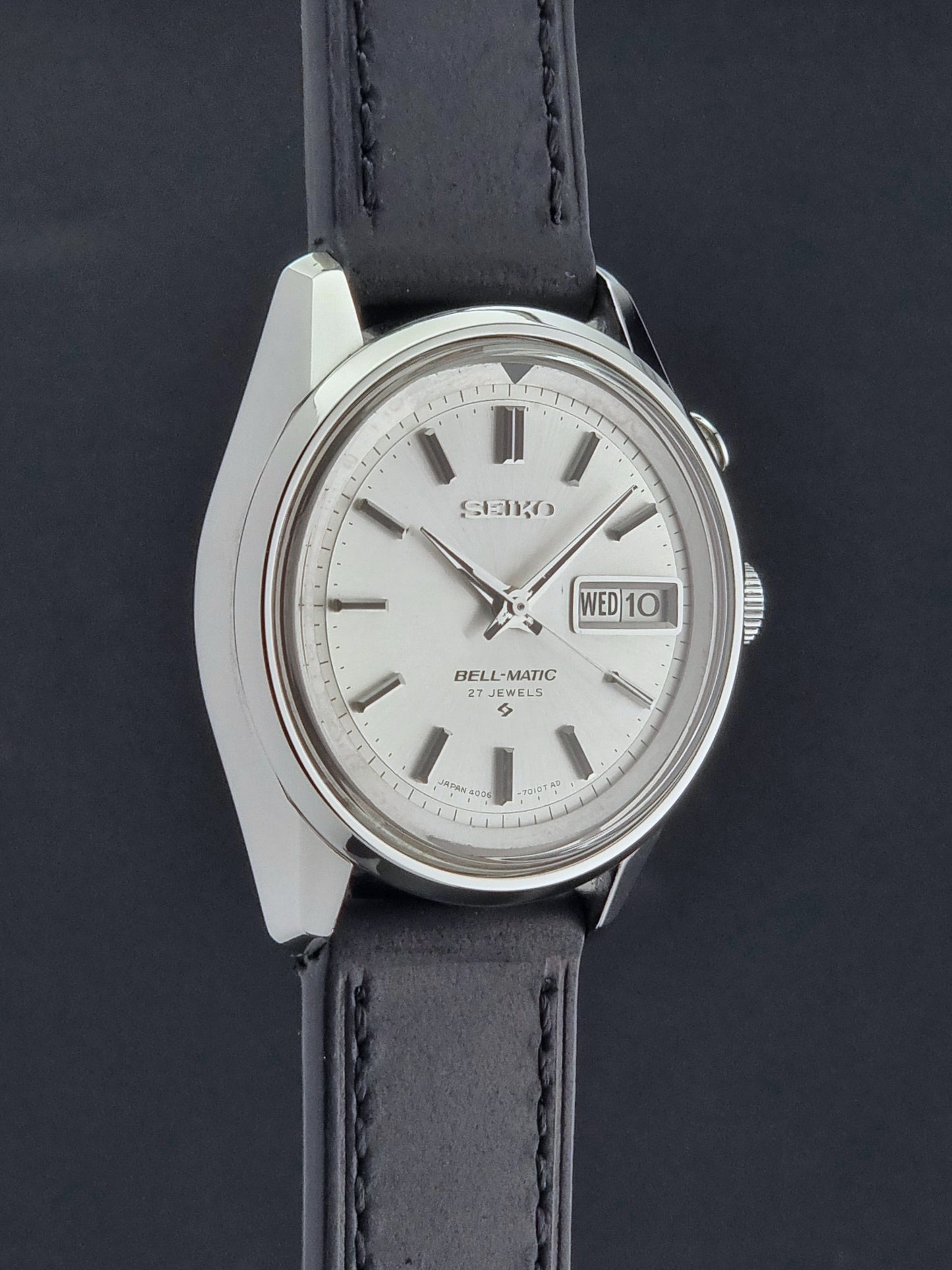 Vintage Seiko Alarm Wristwatch Bell-Matic 4006-7010 with black leather strap on a dark surface side profile view