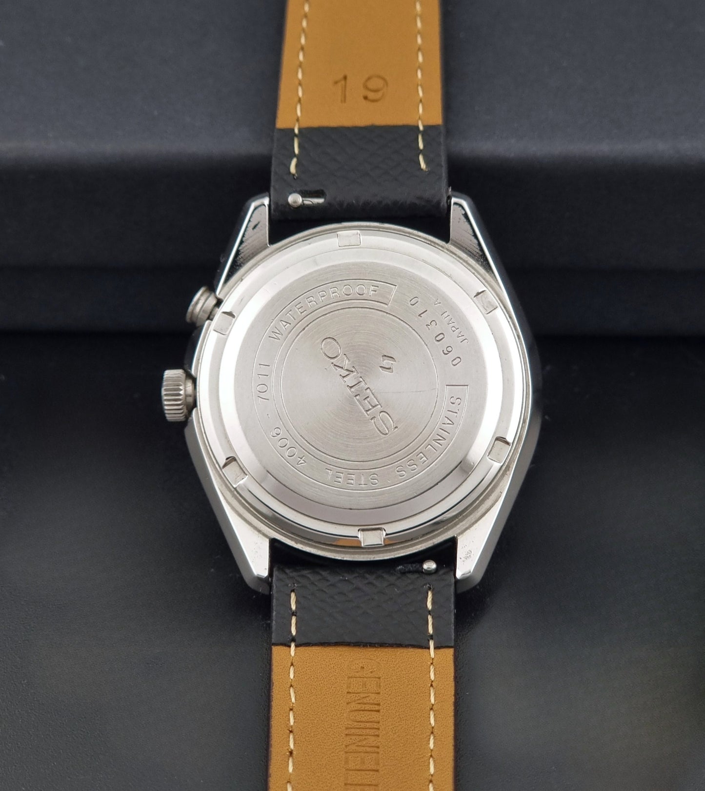 Vintage Seiko Alarm Wristwatch Bell-Matic 4006-7011 with a black strap on a dark background back view