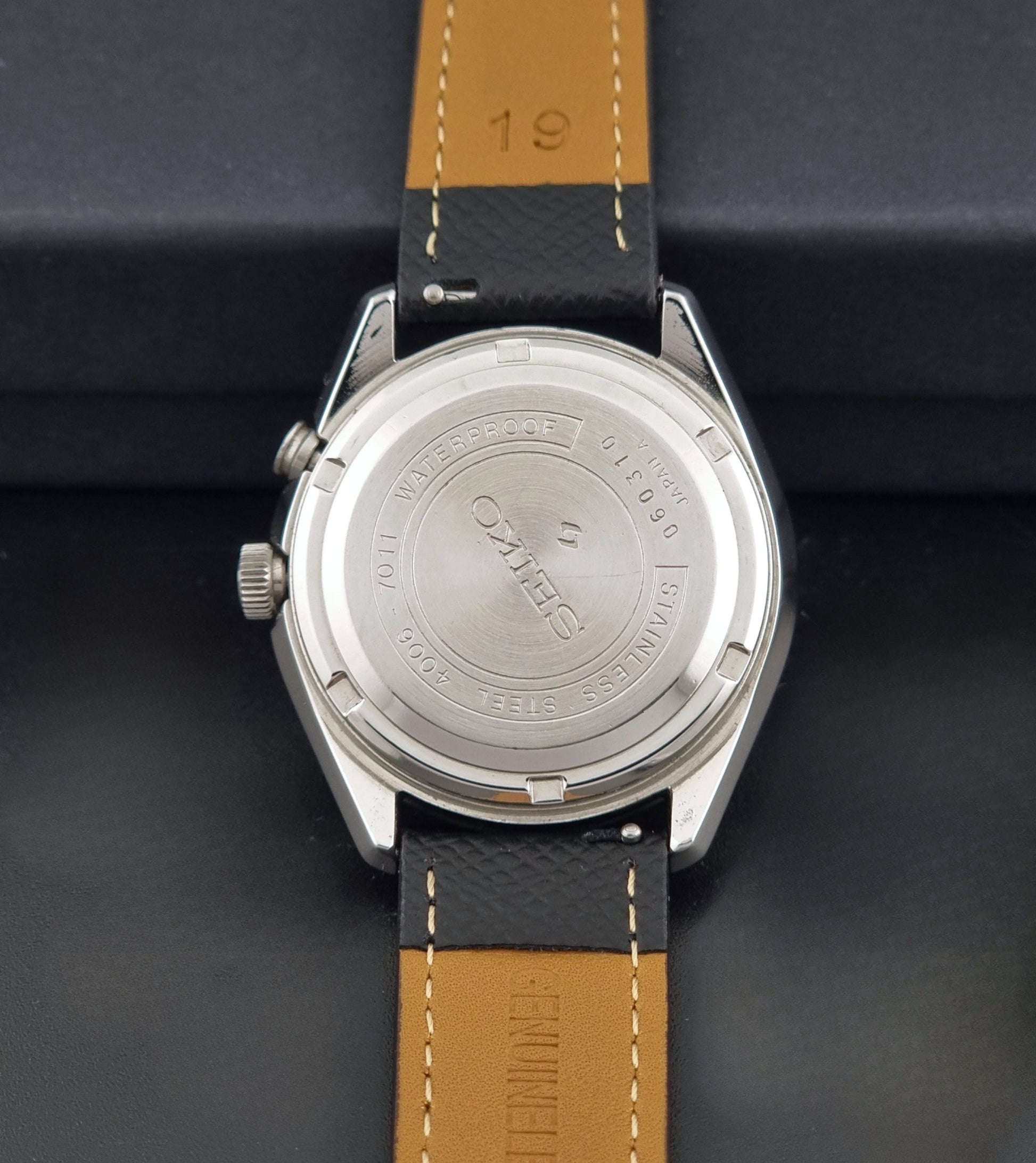 Vintage Seiko Alarm Wristwatch Bell-Matic 4006-7011 with a black strap on a dark background back view