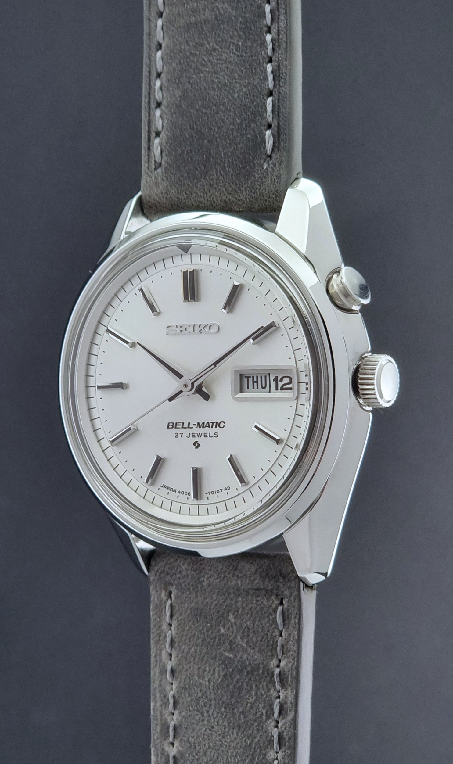 Vintage Seiko Alarm Wristwatch Bell-Matic 4006-7011 with a grey strap on a black background crown profile view