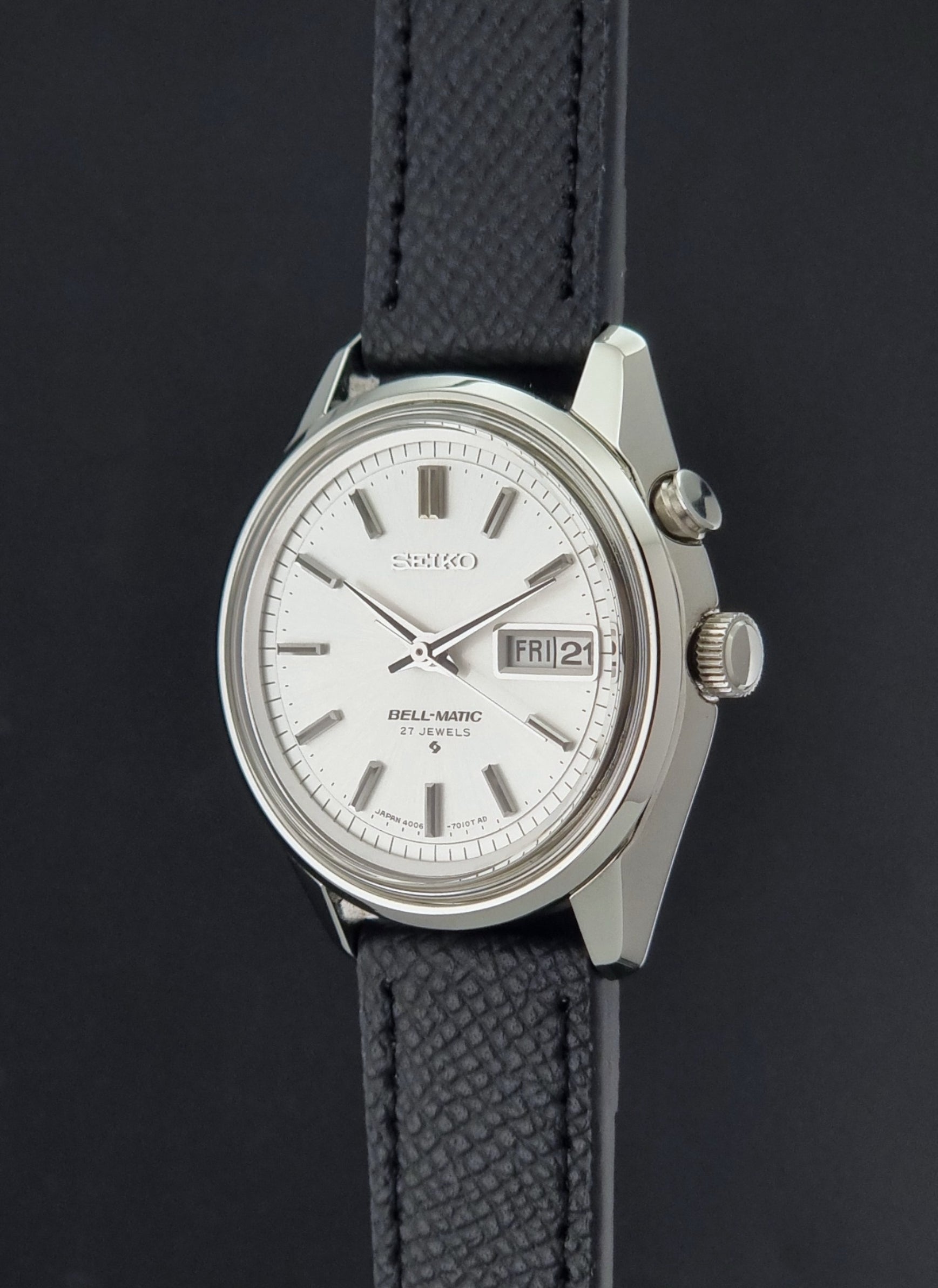 Vintage Seiko Alarm Wristwatch Bell-Matic 4006-7011 with a black strap on a dark background crown profile view
