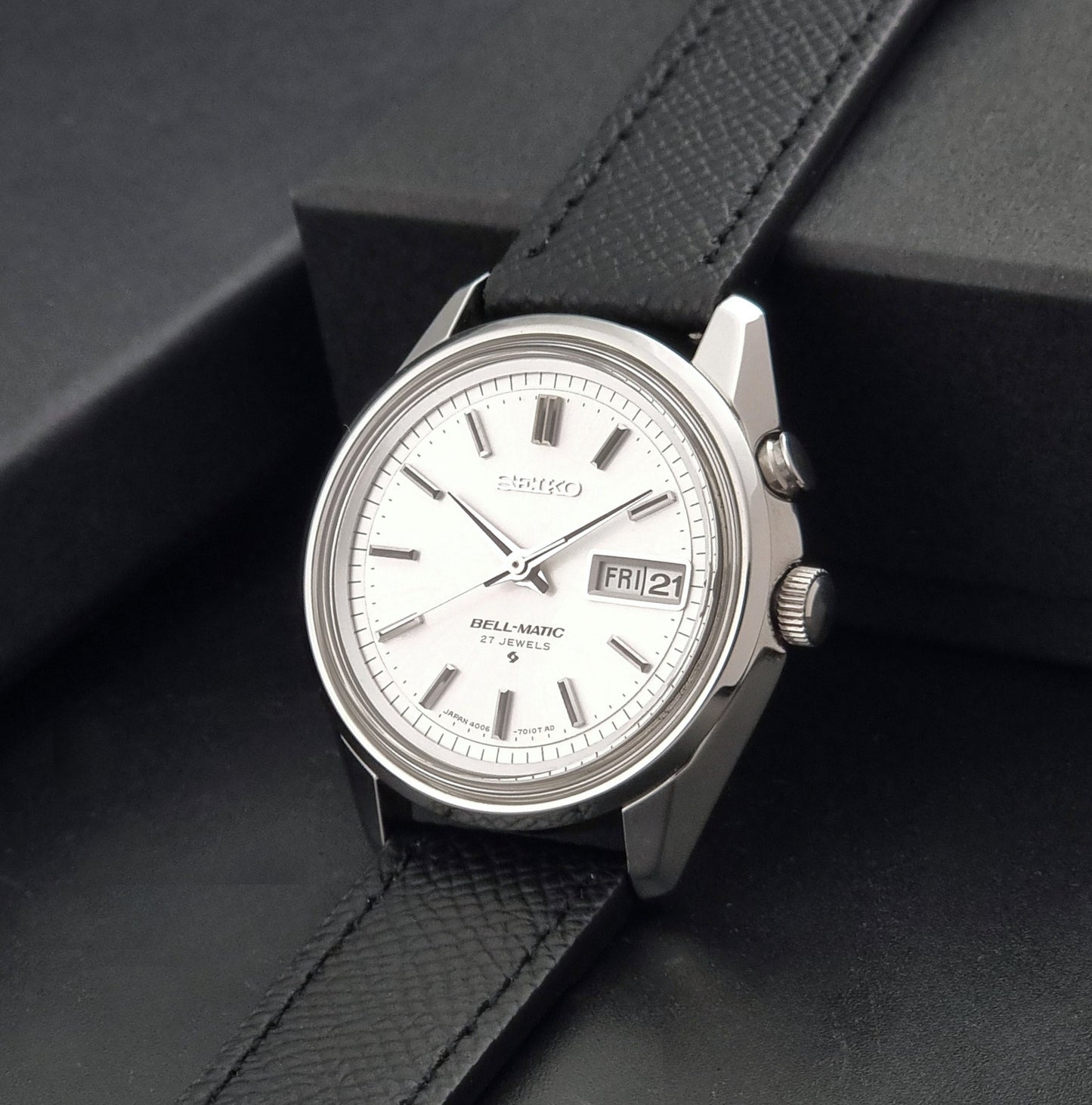 Vintage Seiko Alarm Wristwatch Bell-Matic 4006-7011 with a black strap on a dark background crown view