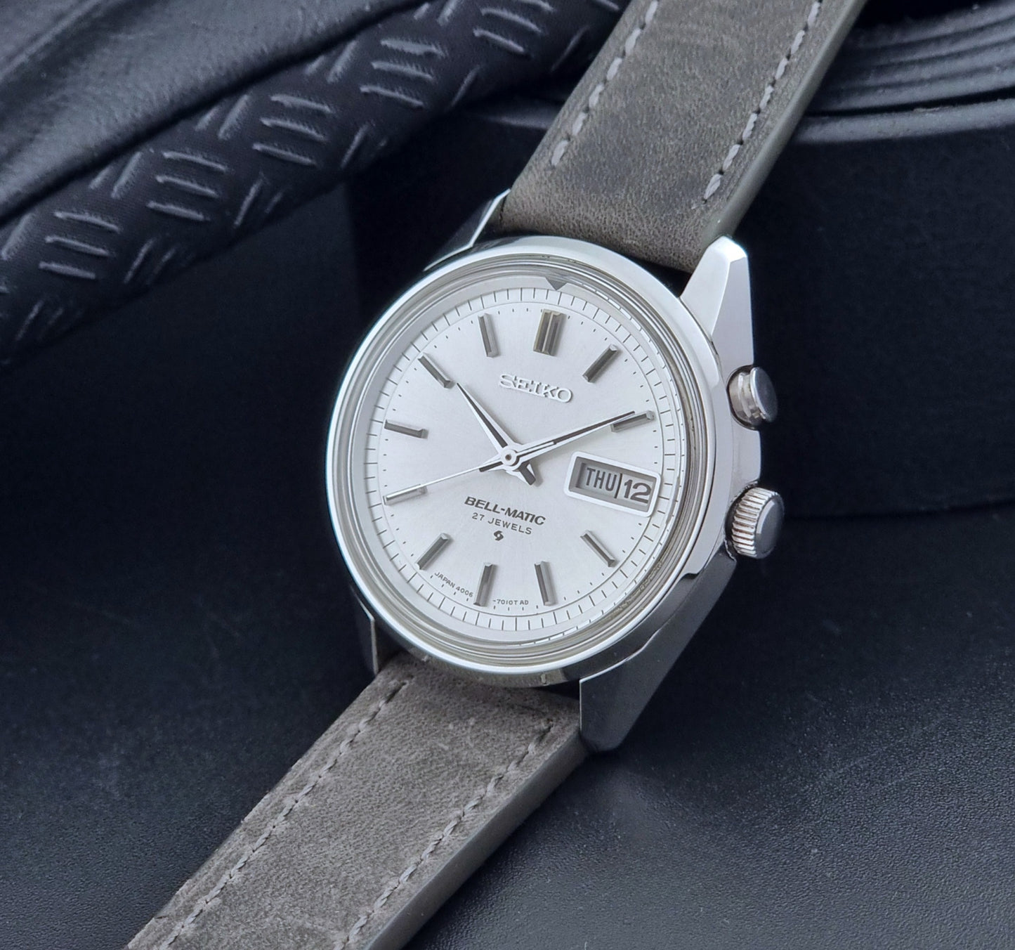 Vintage Seiko Alarm Wristwatch Bell-Matic 4006-7011 with a grey strap on a black background crown view