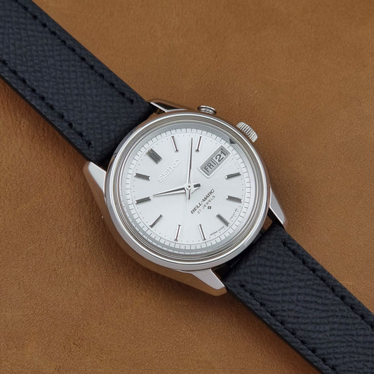 Vintage Seiko Alarm Wristwatch Bell-Matic 4006-7011 with a black strap on a brown background dial