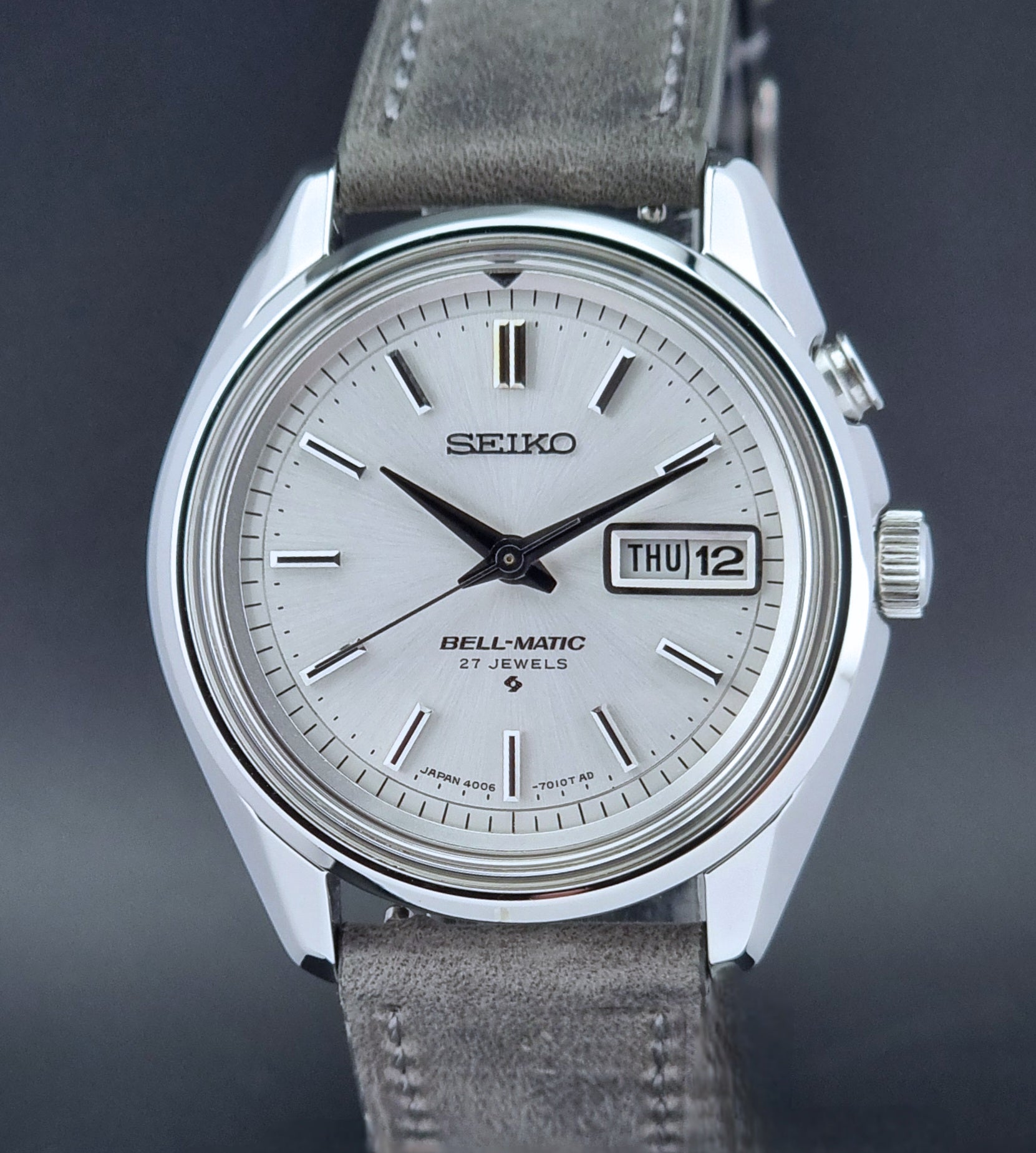 Vintage Seiko Alarm Wristwatch Bell-Matic 4006-7011 with a grey strap on a black background dial view