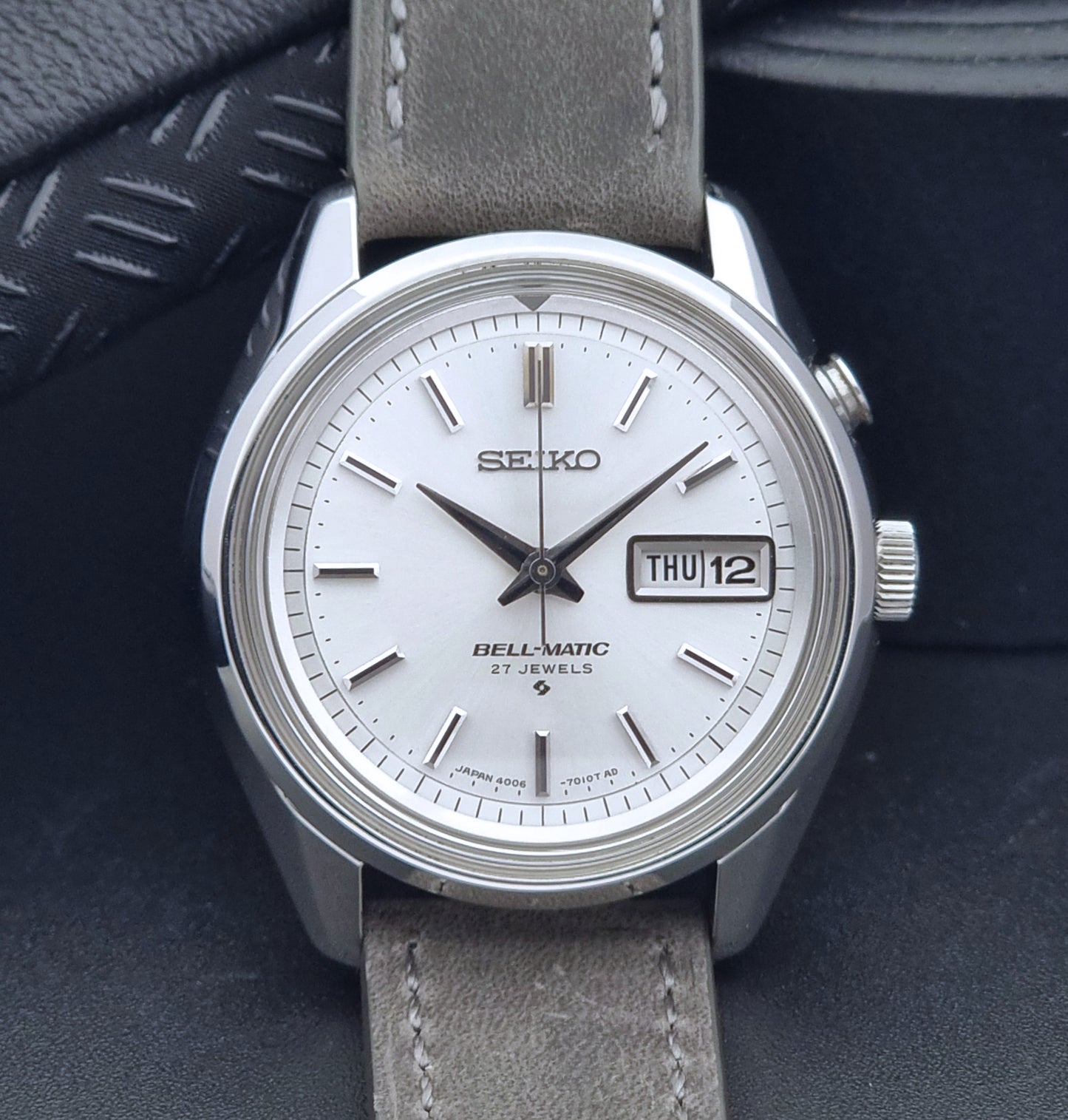 Vintage Seiko Alarm Wristwatch Bell-Matic 4006-7011 with a grey strap on a black background close up dial view