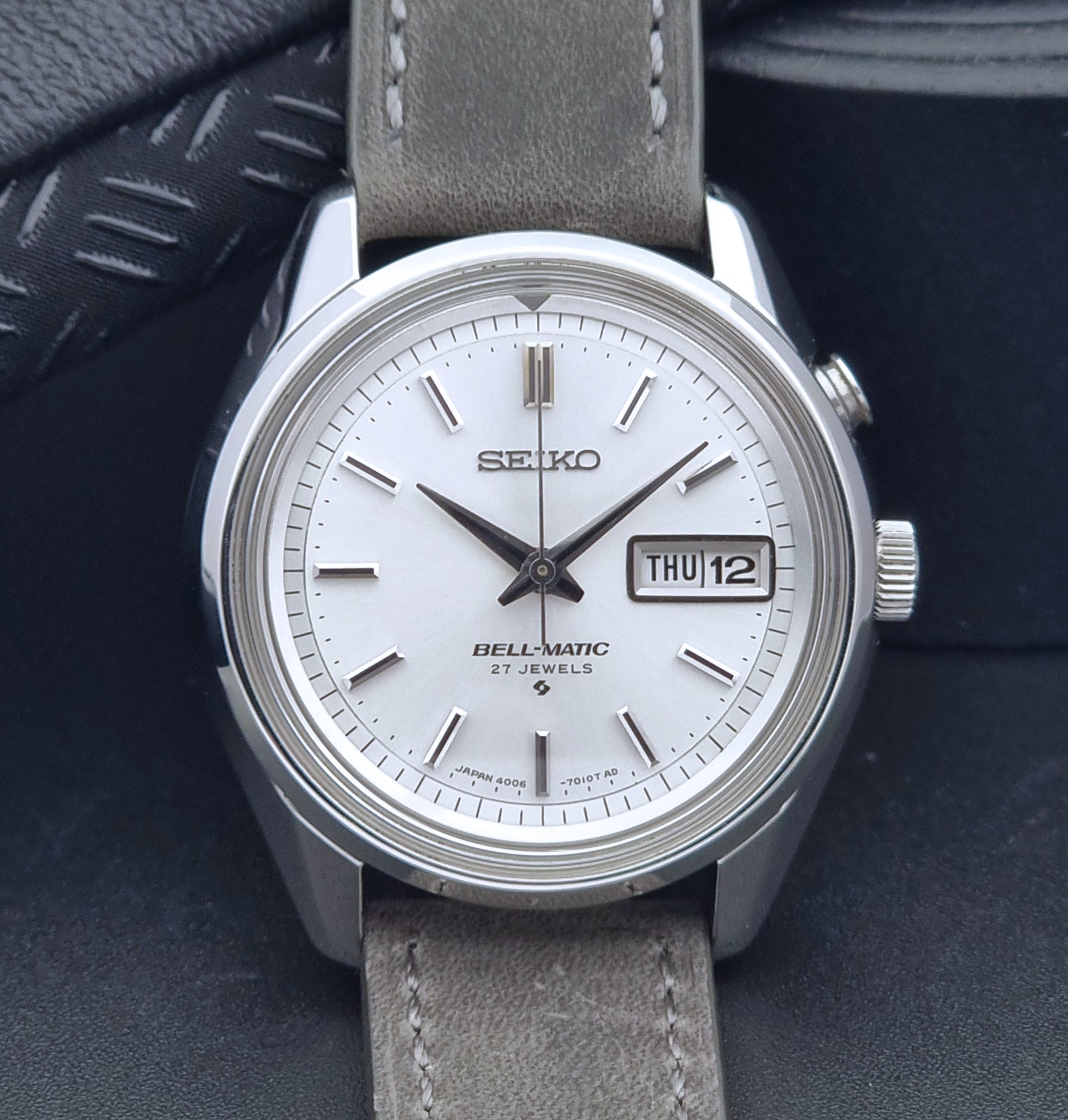 Vintage Seiko Alarm Wristwatch Bell-Matic 4006-7011 with a grey strap on a black background close up dial view