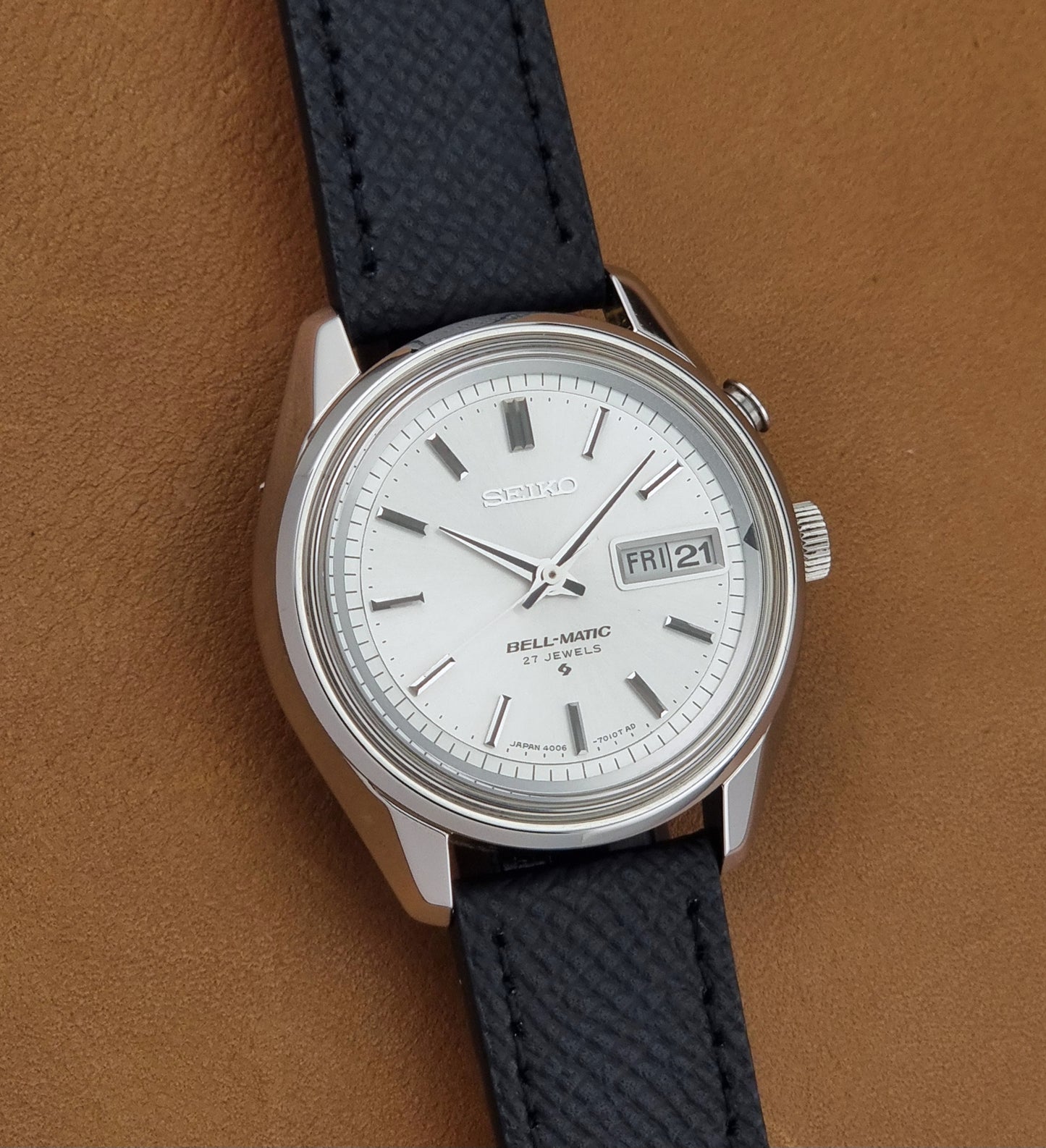 Vintage Seiko Alarm Wristwatch Bell-Matic 4006-7011 with a black strap on a brown background front