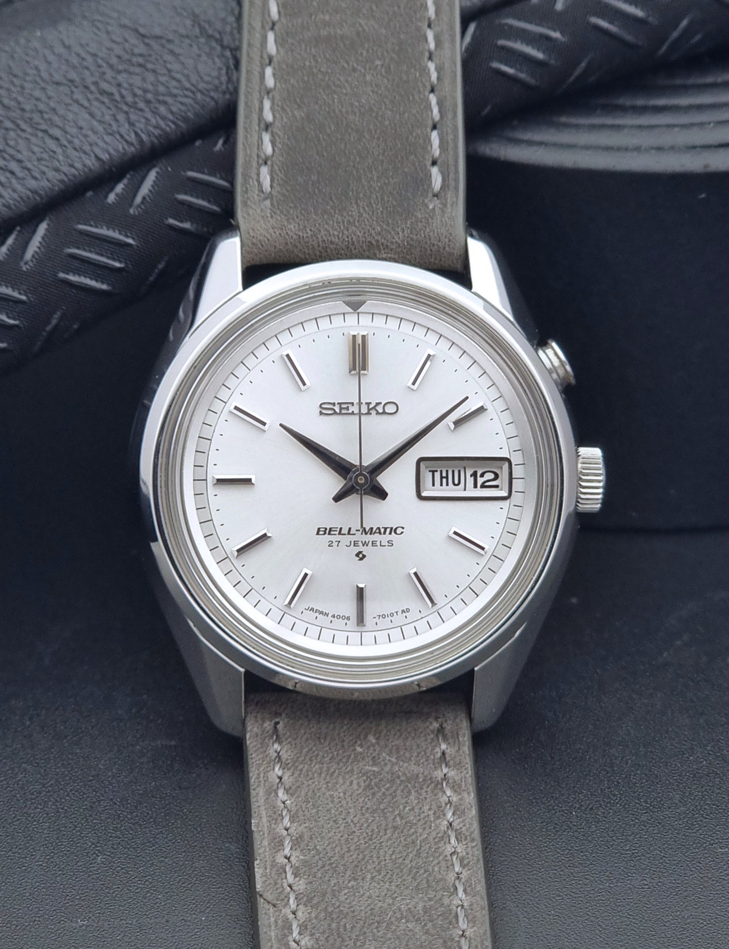 Vintage Seiko Alarm Wristwatch Bell-Matic 4006-7011 with a grey strap on a black background front view