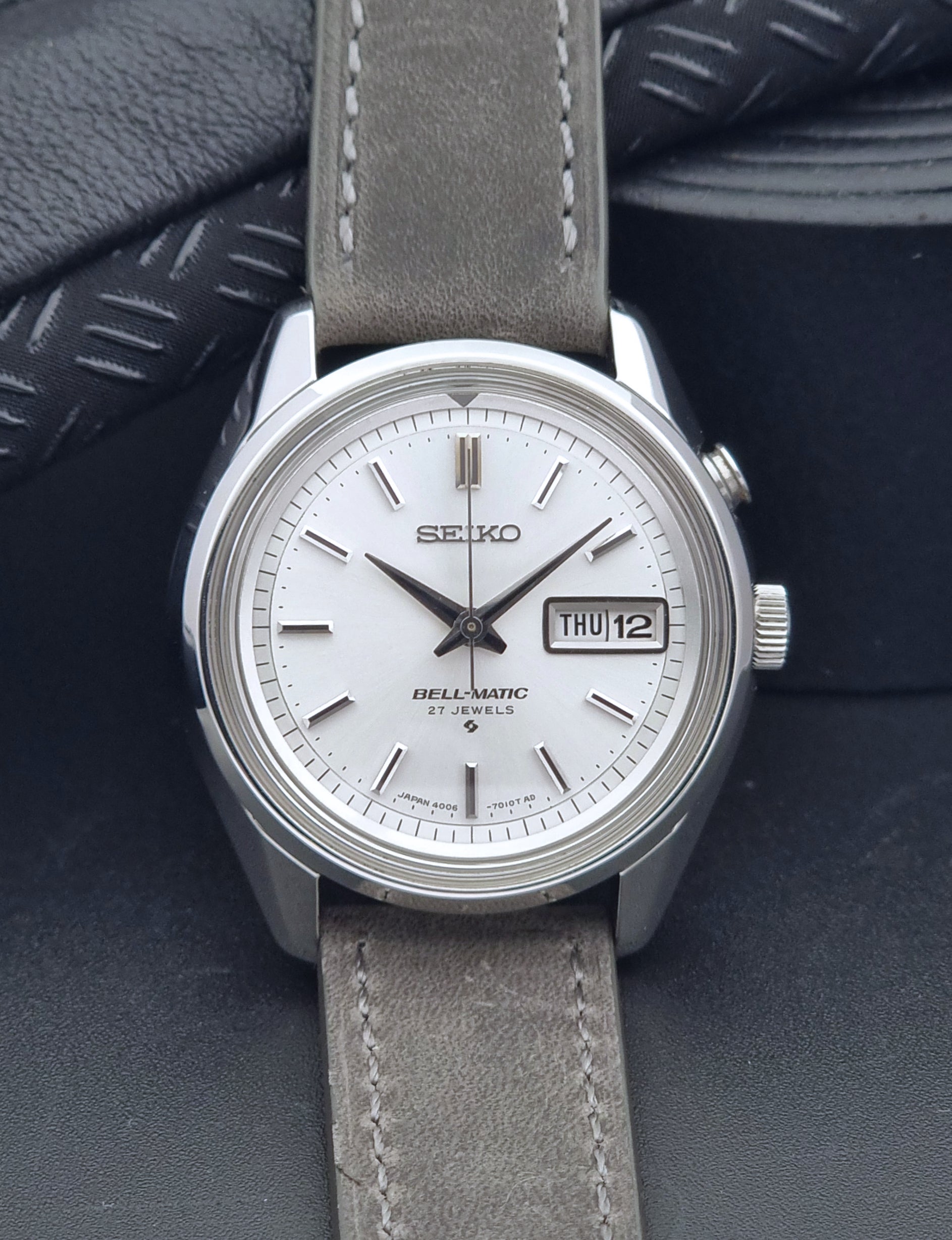 Vintage Seiko Alarm Wristwatch Bell-Matic 4006-7011 with a grey strap on a black background front view