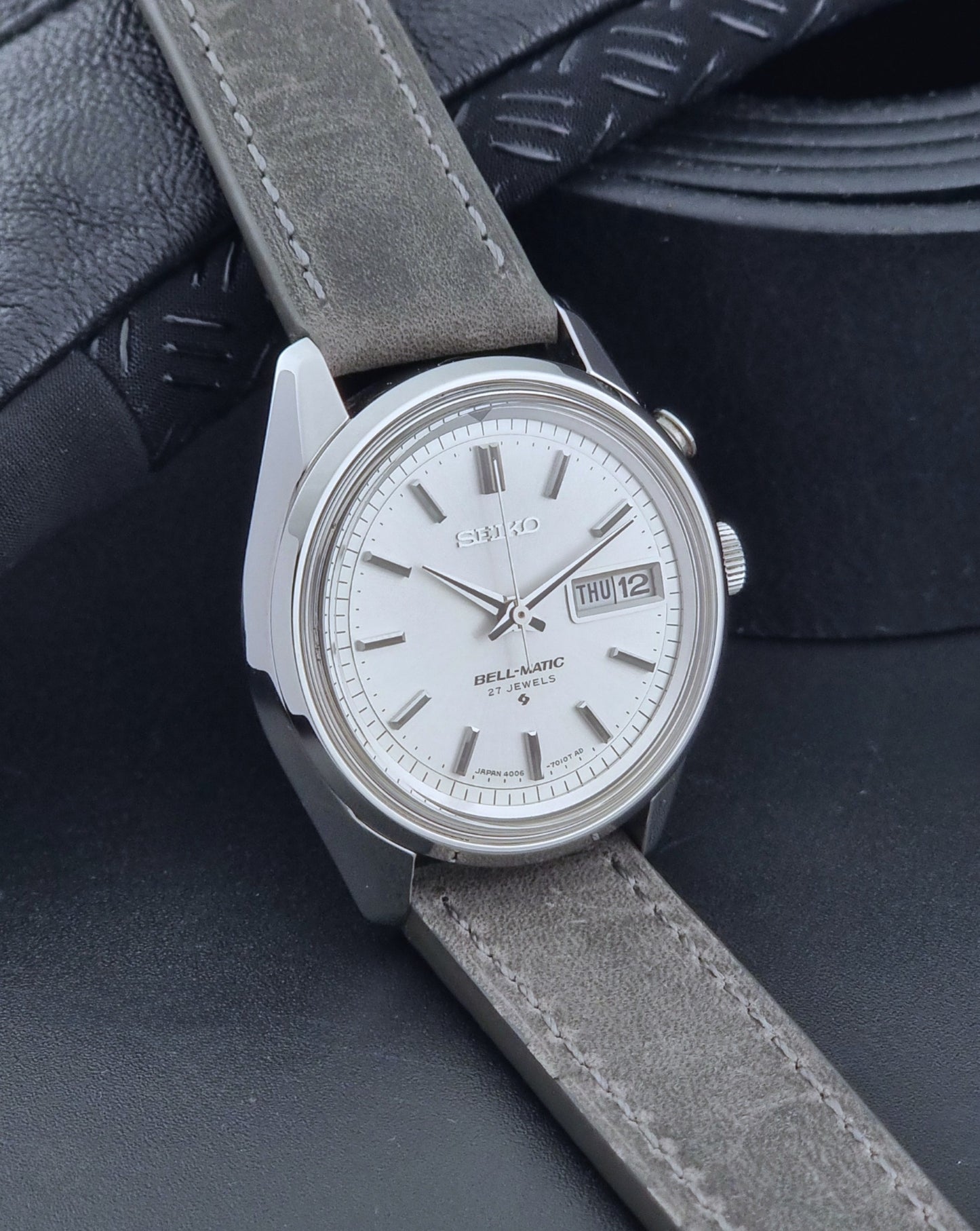 Vintage Seiko Alarm Wristwatch Bell-Matic 4006-7011 with a grey strap on a black background side view