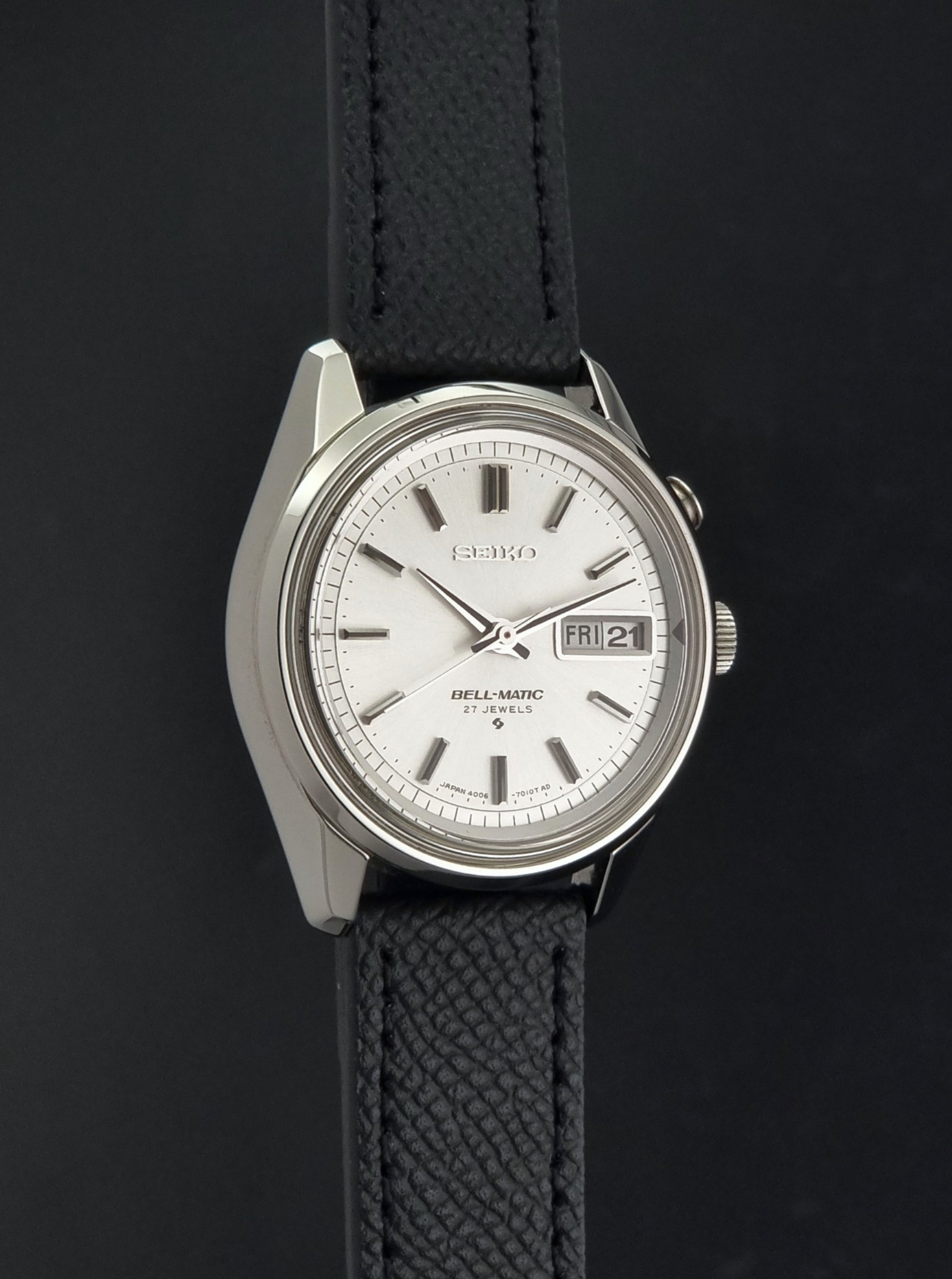 Vintage Seiko Alarm Wristwatch Bell-Matic 4006-7011 with a black strap on a dark background side profile view