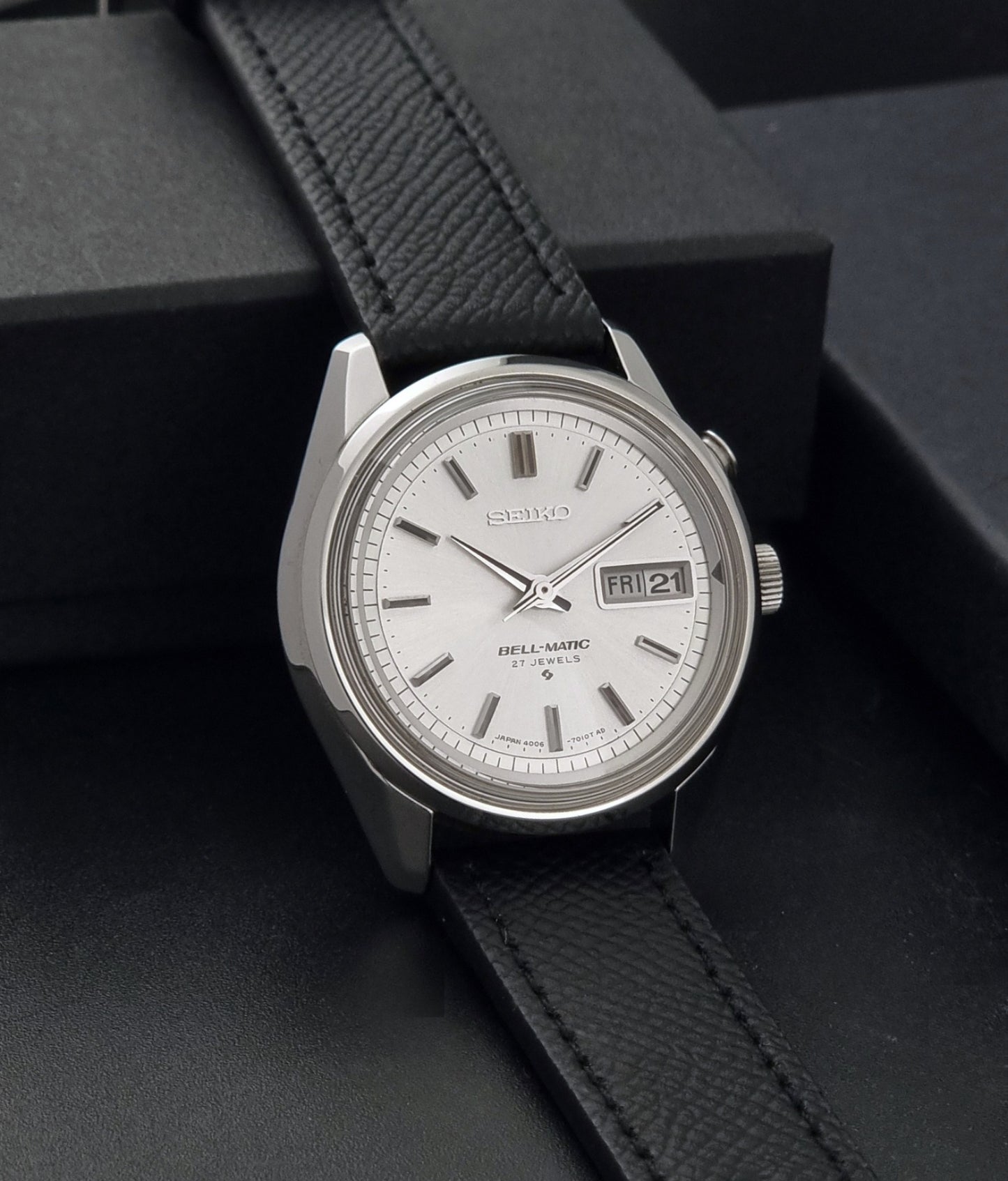 Vintage Seiko Alarm Wristwatch Bell-Matic 4006-7011 with a black strap on a dark background side view