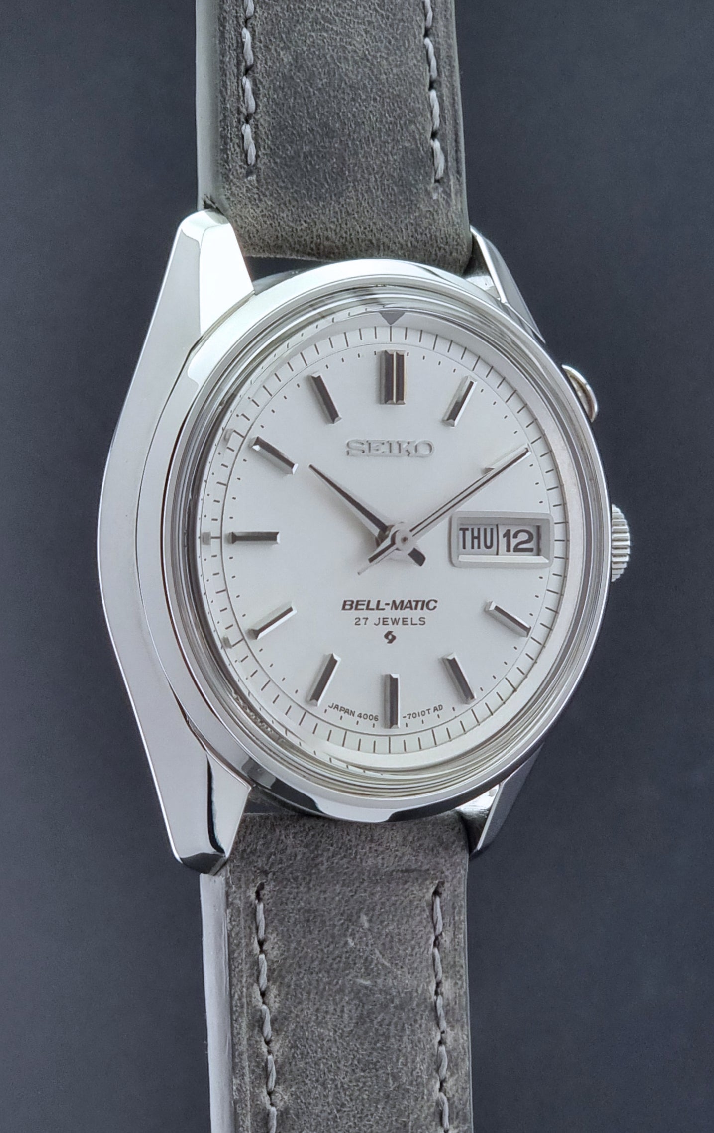 Vintage Seiko Alarm Wristwatch Bell-Matic 4006-7011 with a grey strap on a black background side profile view