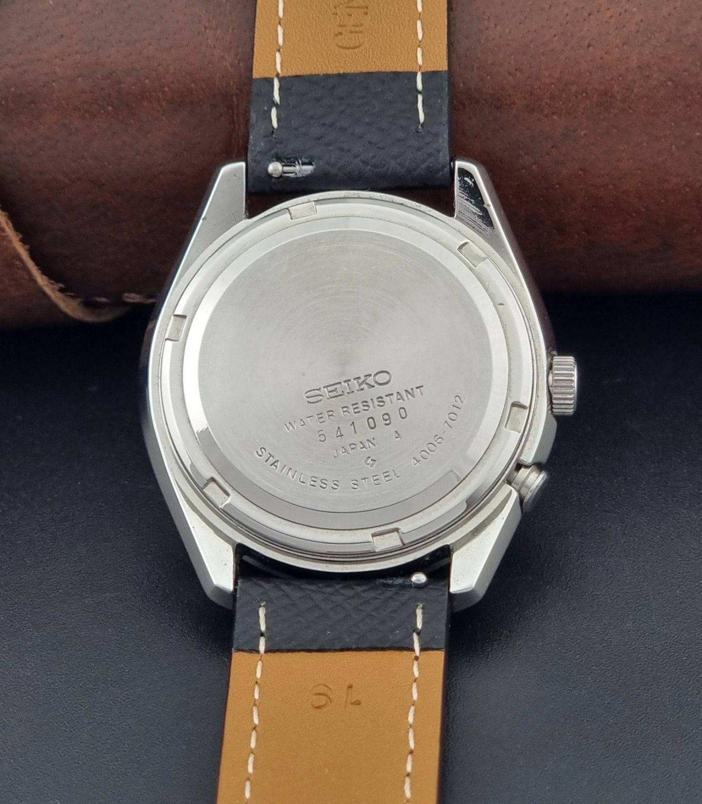 Vintage Seiko Alarm Watch Bell-Matic 4006-7012 with a grey dial and black leather strap on a dark surface case back view