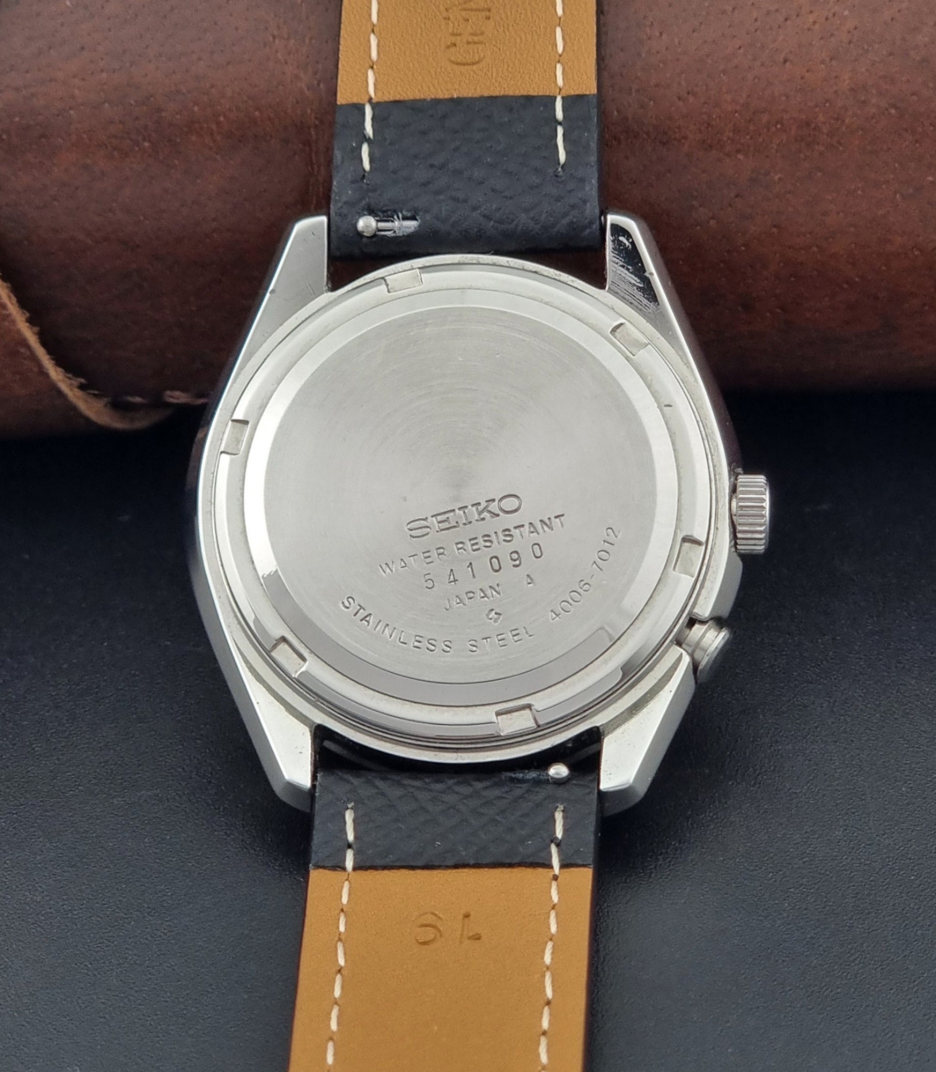 Vintage Seiko Alarm Watch Bell-Matic 4006-7012 with a grey dial and black leather strap on a dark surface case back view