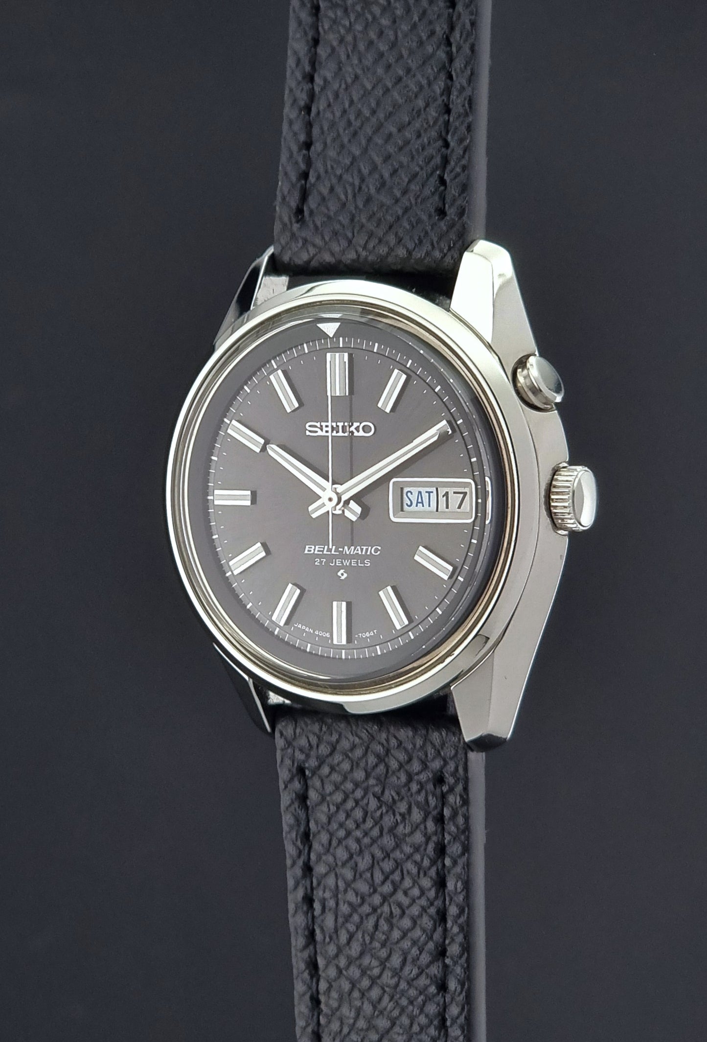 Vintage Seiko Alarm Watch Bell-Matic 4006-7012 with a grey dial and black leather strap on a dark surface crown profile view