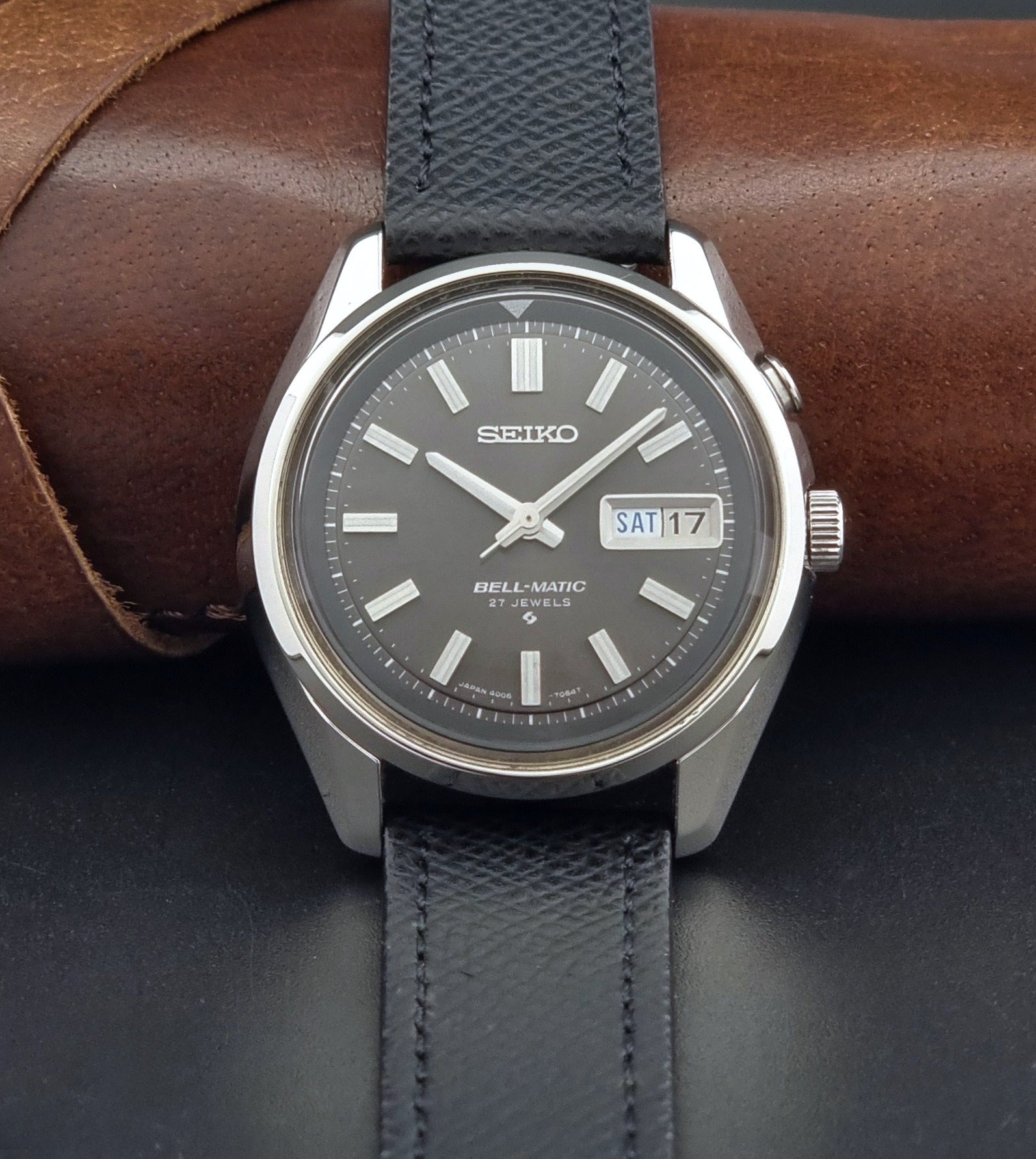Vintage Seiko Alarm Watch Bell-Matic 4006-7012 with a grey dial and black leather strap on a dark surface front view
