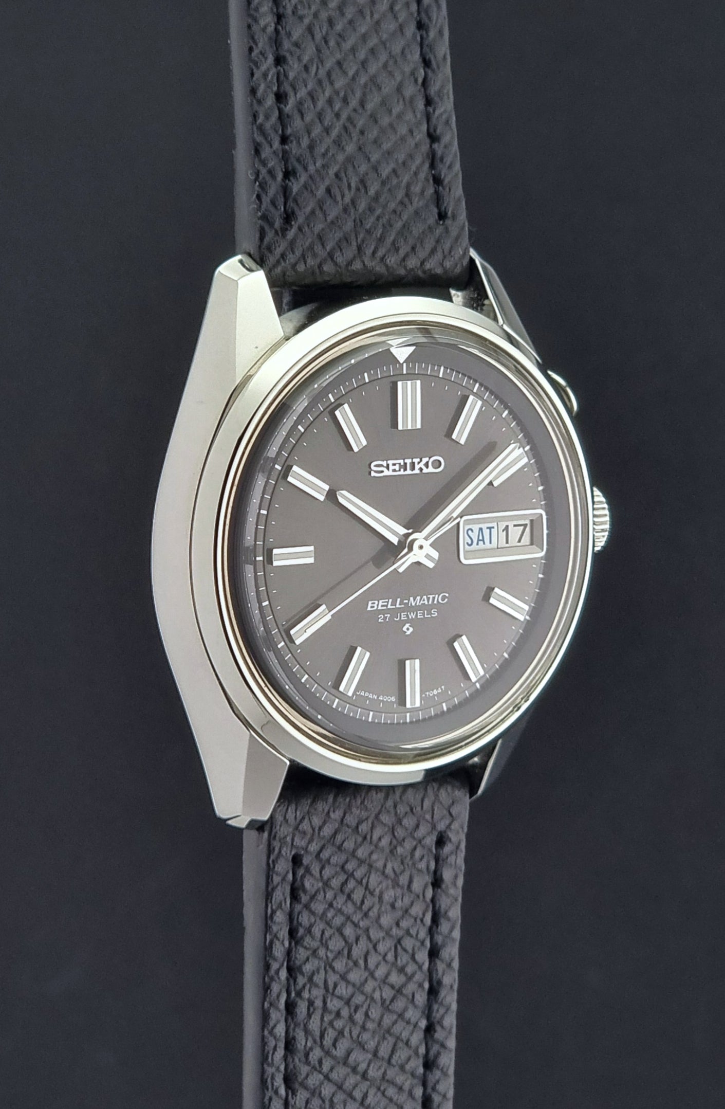 Vintage Seiko Alarm Watch Bell-Matic 4006-7012 with a grey dial and black leather strap on a dark surface side profile view