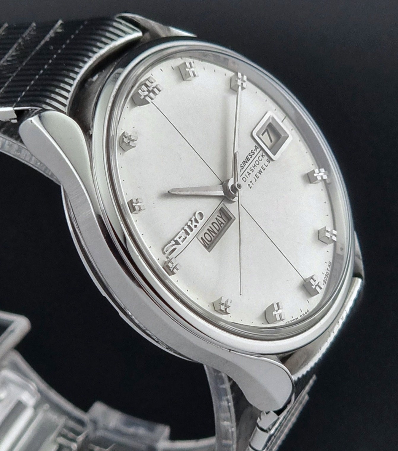 Close-up of a Seiko watch with a silver metal strap on a black background