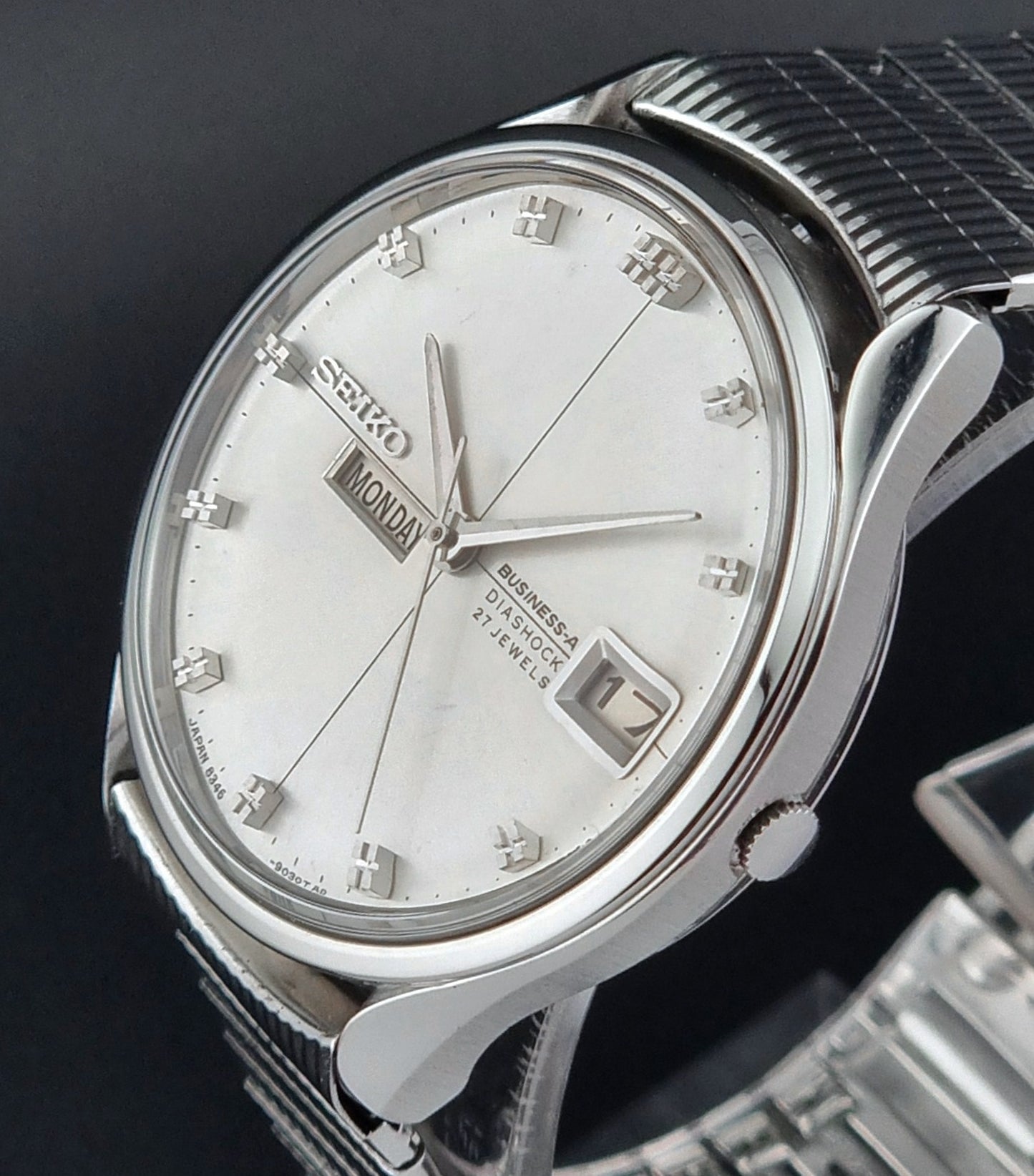 Seiko watch with silver case and white face on a dark background